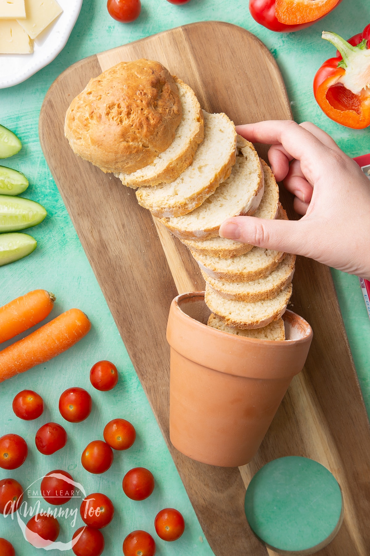 Overhead shot of a hand touching Flowerpot bread served on a wooden plate