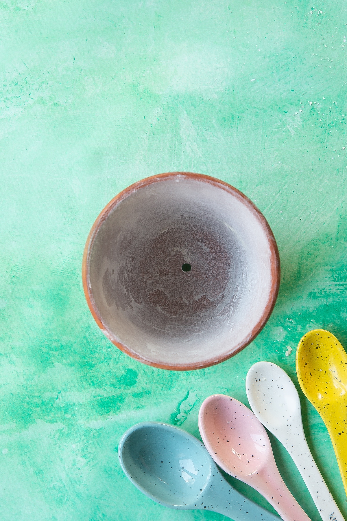 Overhead shot of the flowerpot with butter beside coloured spoons