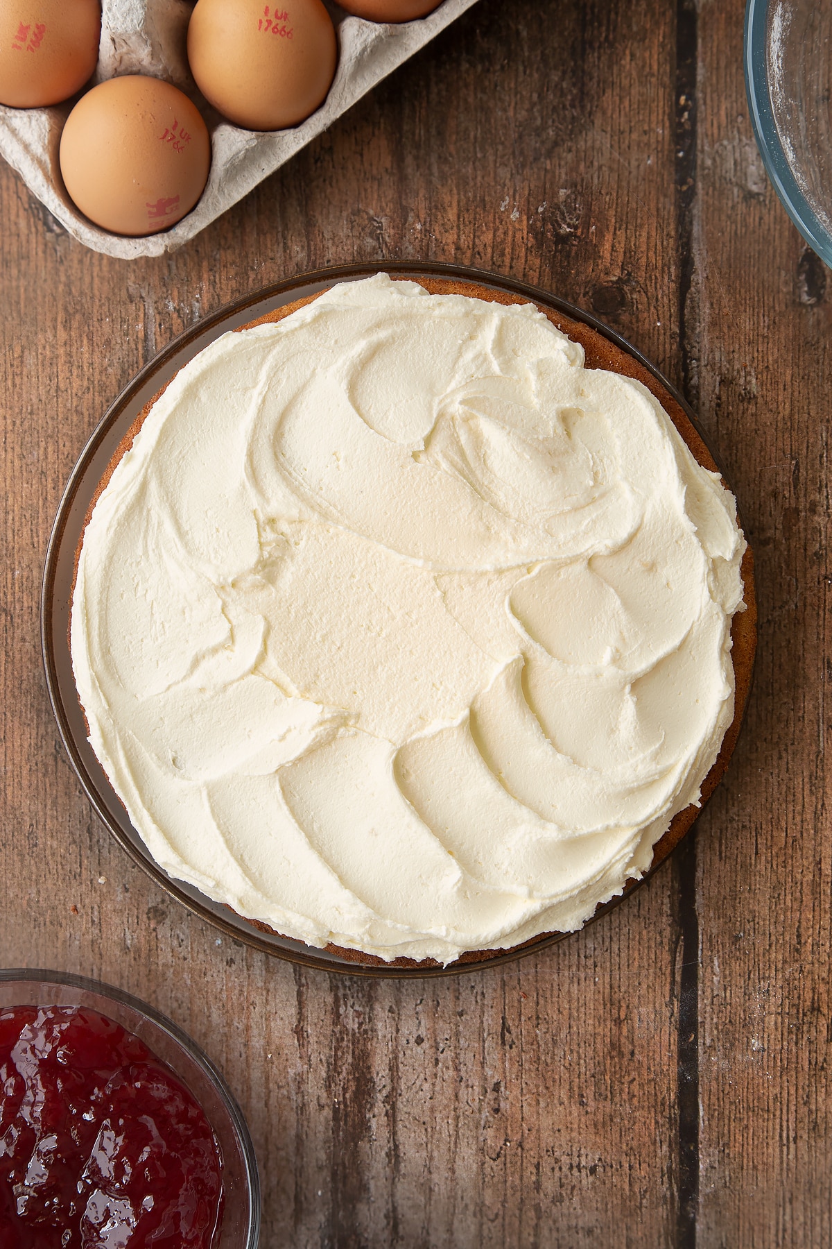 Overhead shot of Golden sponge cake covered in buttercream frosting on a wooden table.