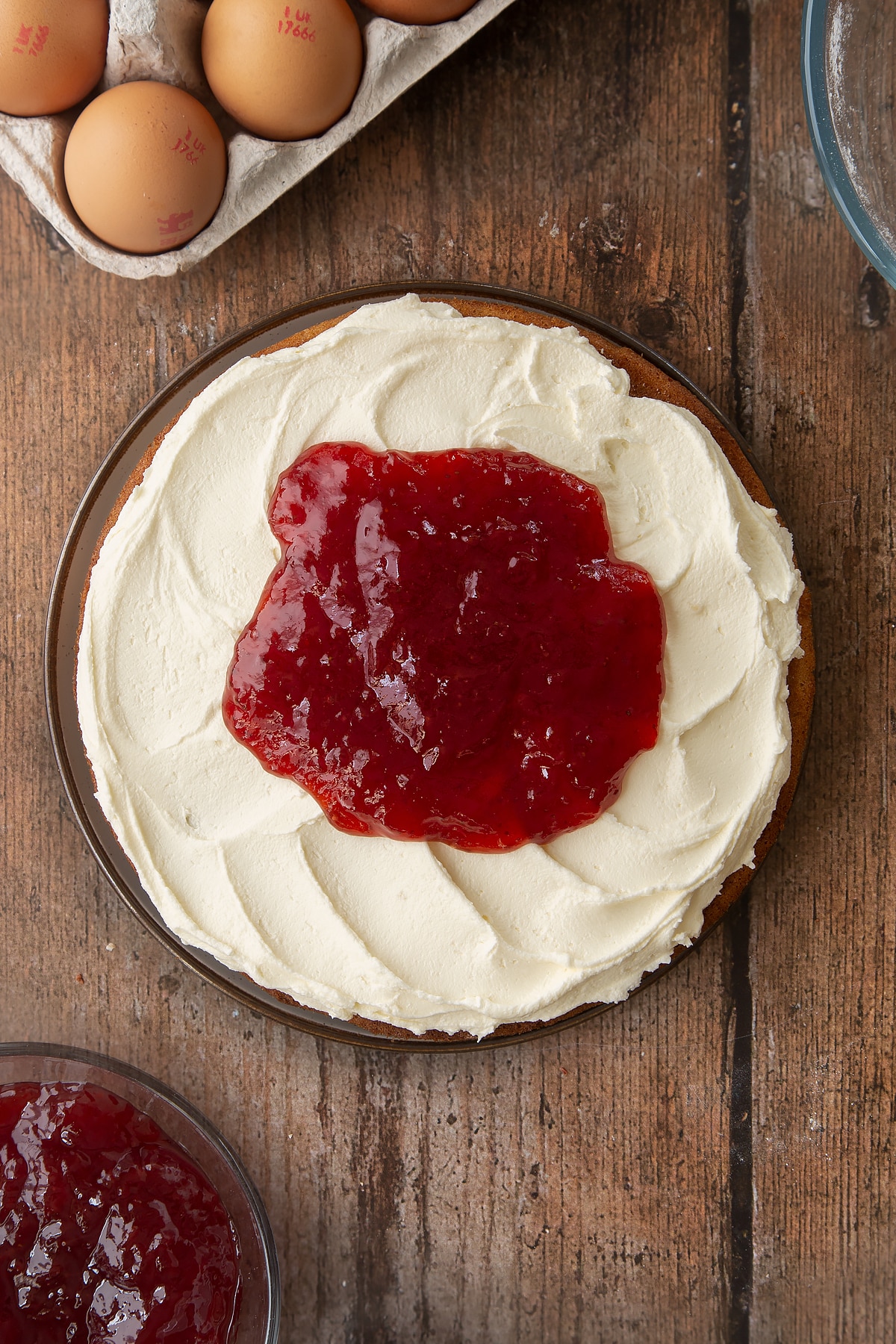 Adding jam on top of the buttercream frosting on the golden syrup sponge cake.