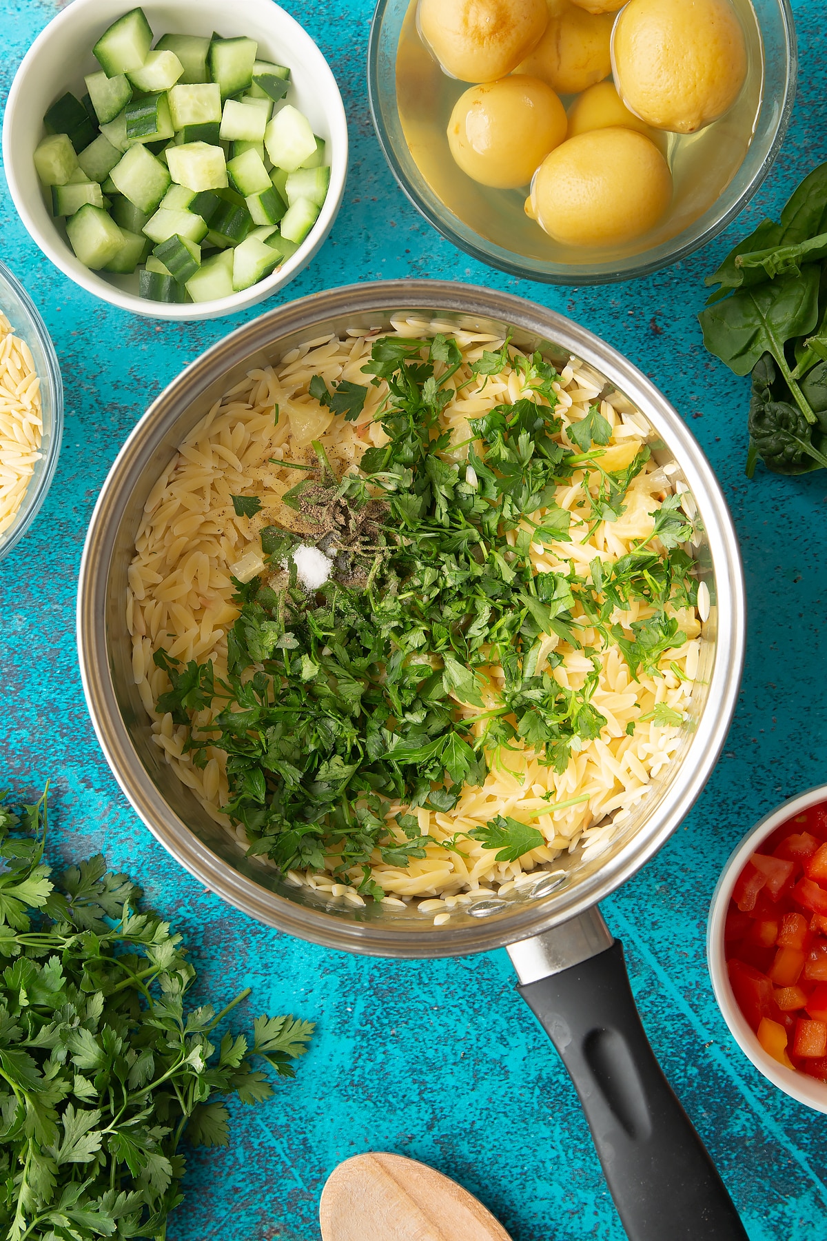 Cooked orzo in a saucepan with preserved lemons, parsley, salt and pepper on top.