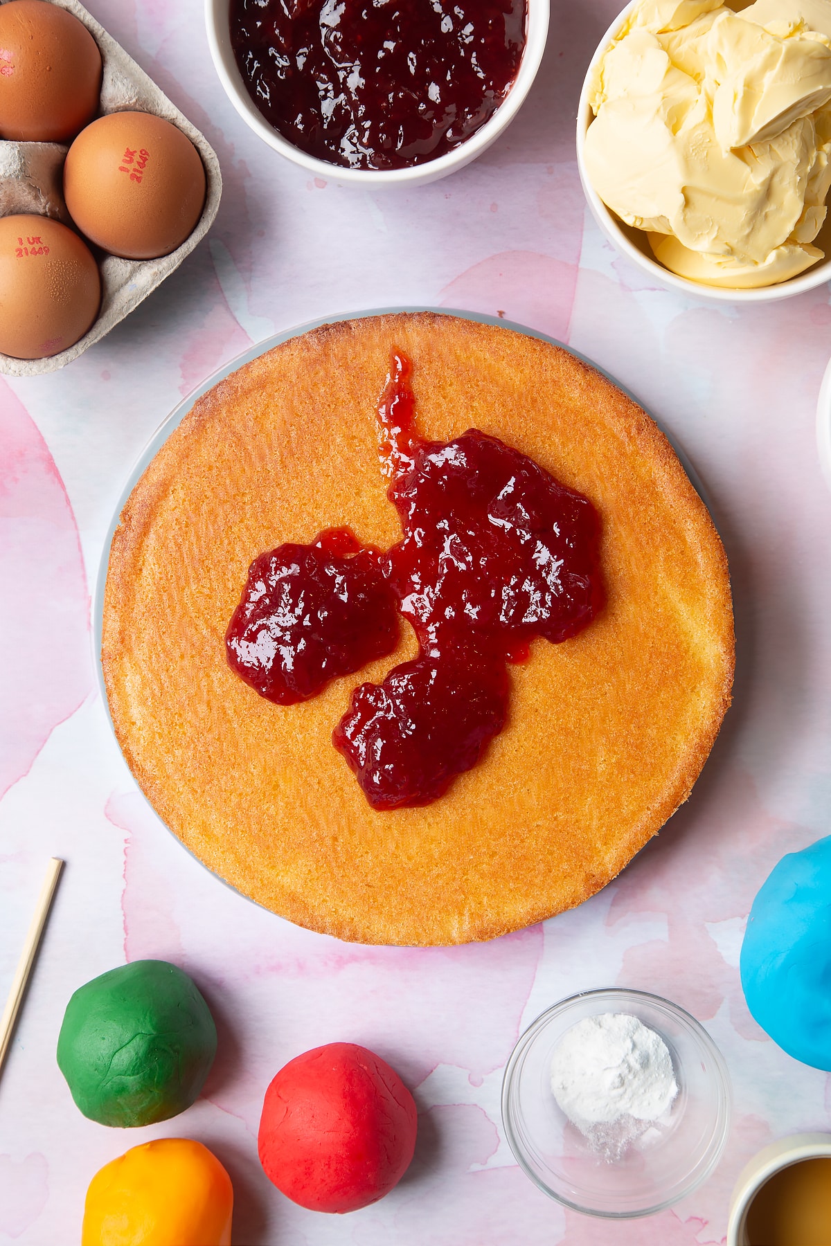 Adding jam to the top of the cake sponge.