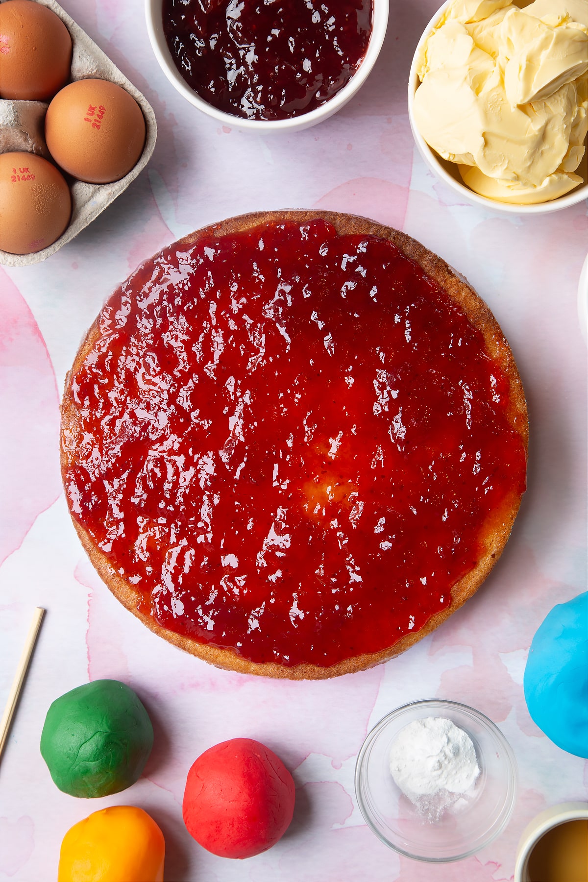 Overhead shot of adding more jam to the top of the second layer of sponge.