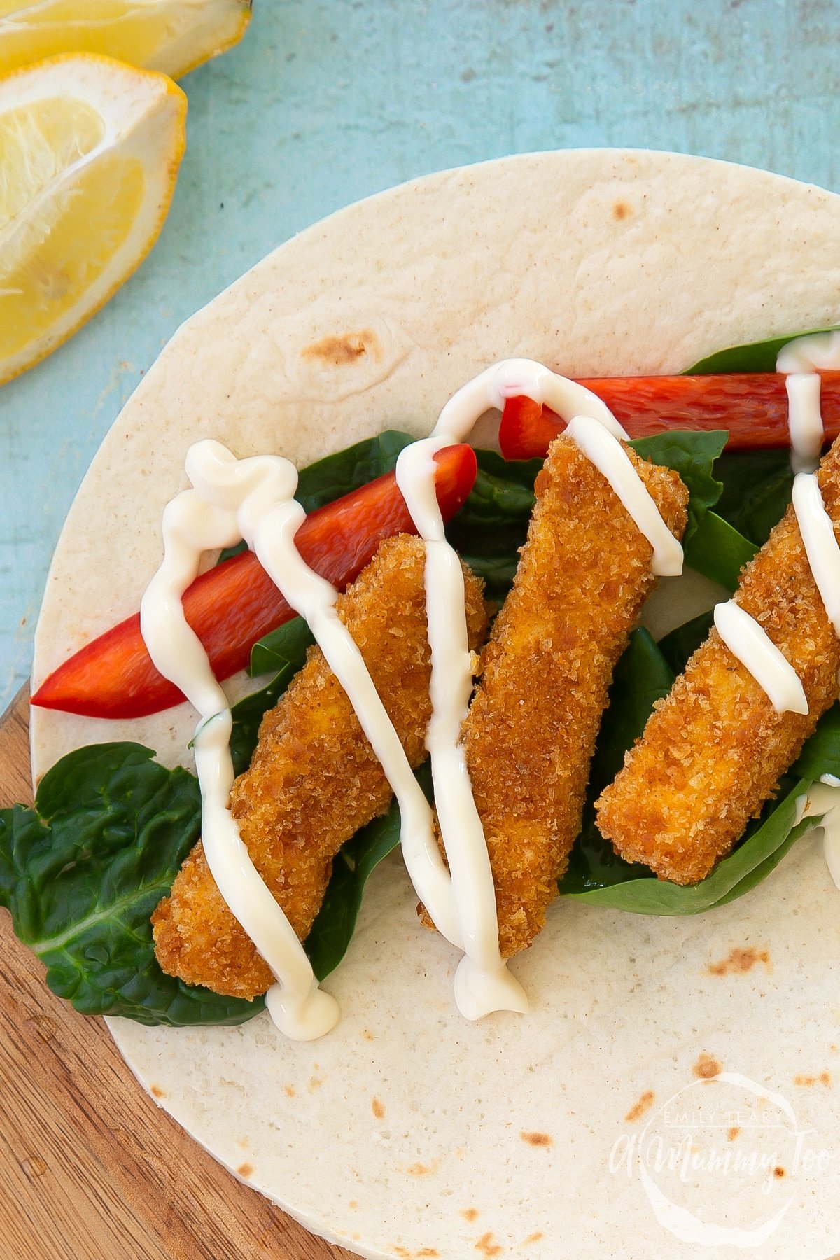 Tofu fingers, with a breadcrumb coating sitting on a wrap with vegetables and a sauce.