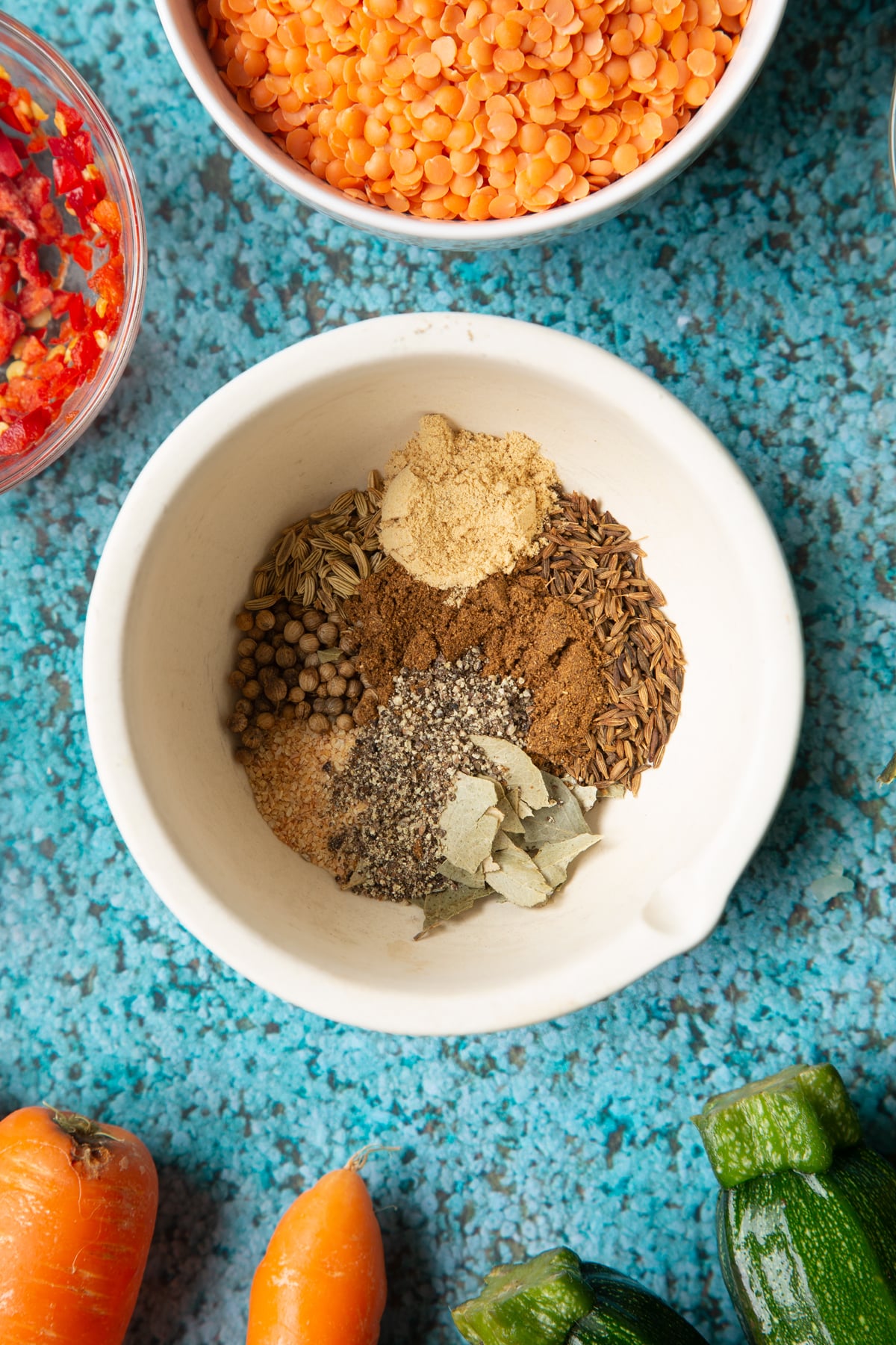 Spices in a mortar. Ingredients to make baked bean curry surround the mortar.