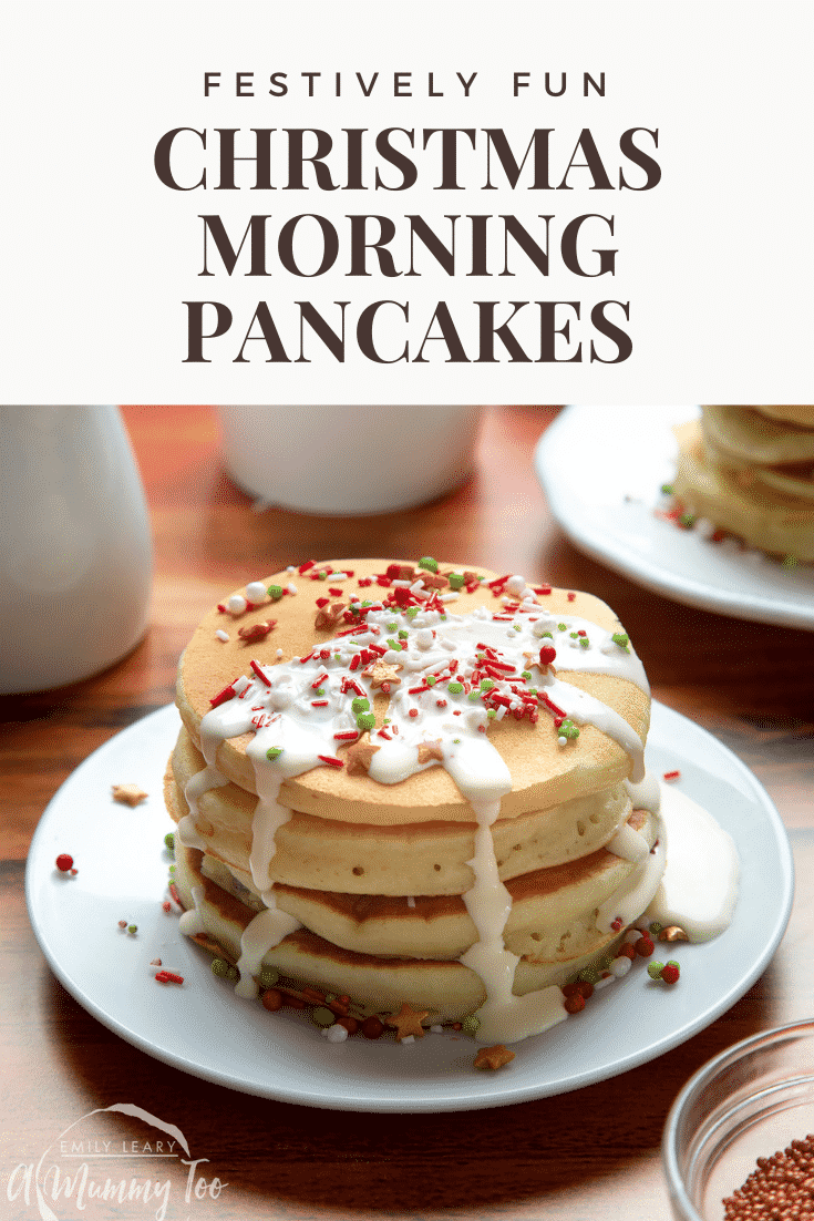 A tall stack pancakes, stacked on a white plate, scattered with festive sprinkles and drizzled with cream. Caption reads: festively fun Christmas morning pancakes