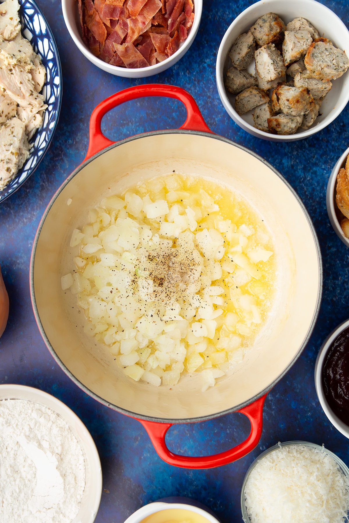 Seasoned chopped onions in a pan. Ingredients to make a leftover Christmas dinner pie surround the pan.