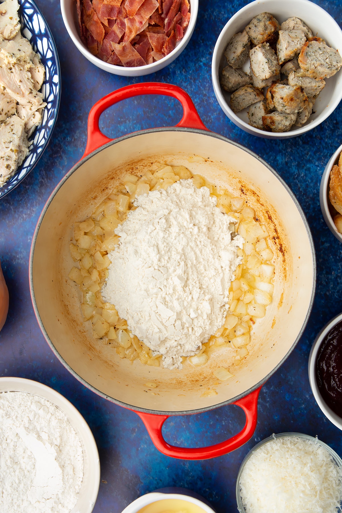 Fried onions and flour in a pan. Ingredients to make a leftover Christmas dinner pie surround the pan.