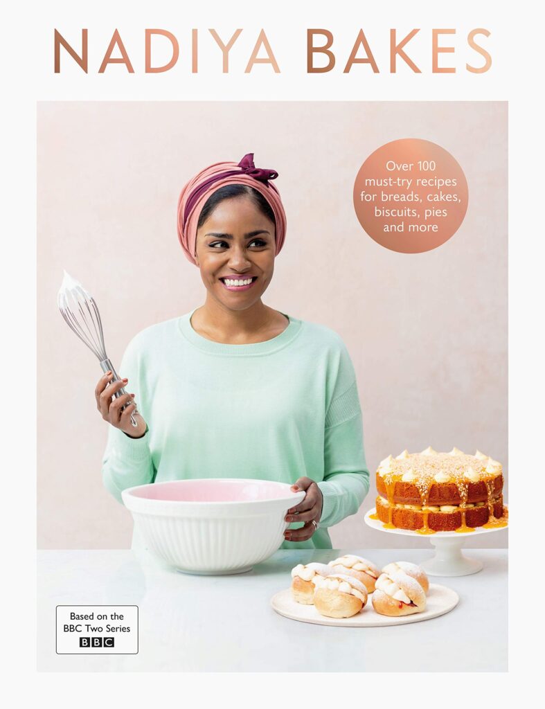 The cover of Nadiya Hussain's book, Nadiya Bakes, which shows Nadiya holding a whisk.