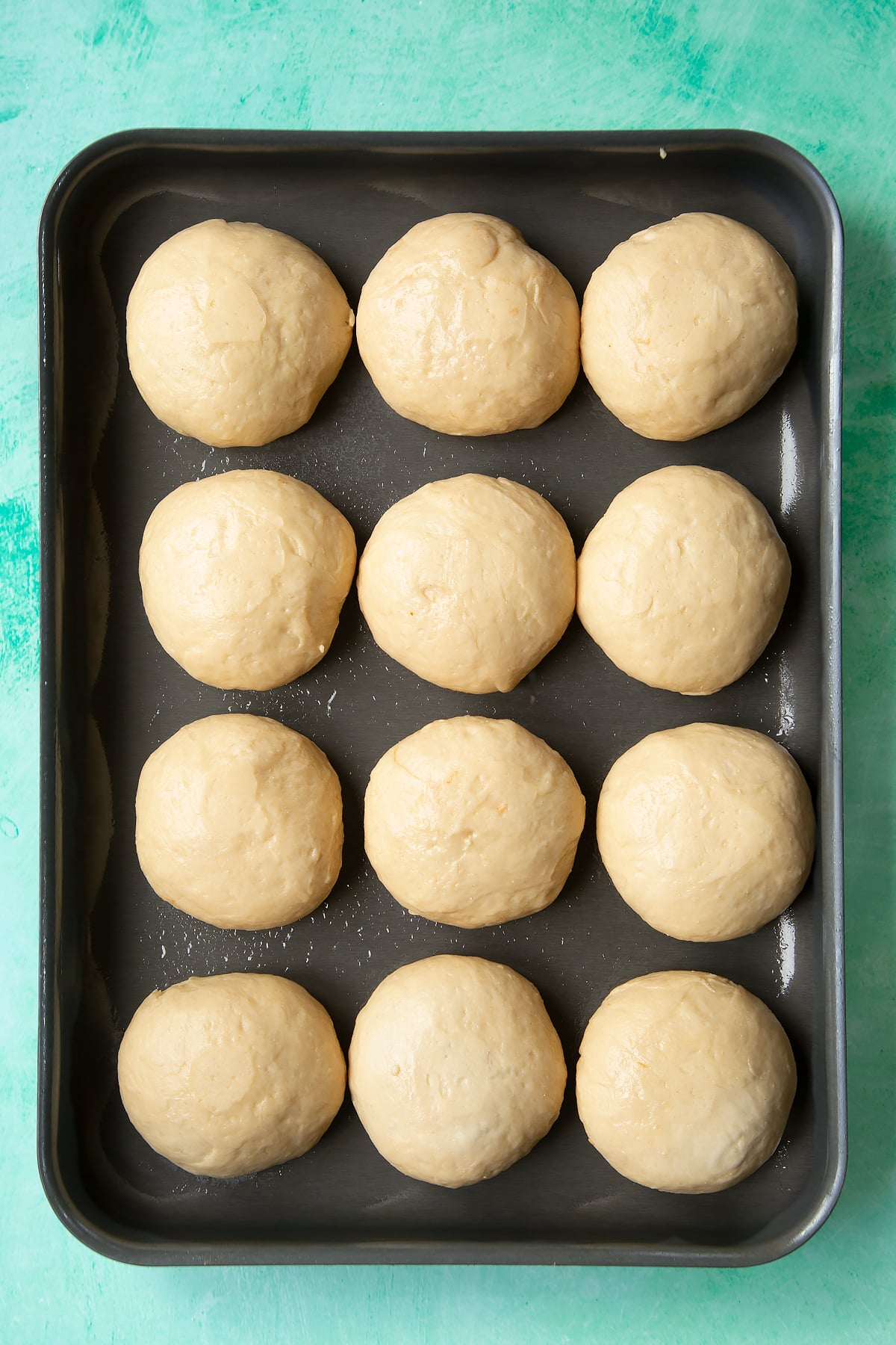 Rested balls of doughy chicken doughnuts turned upside down on a tray.