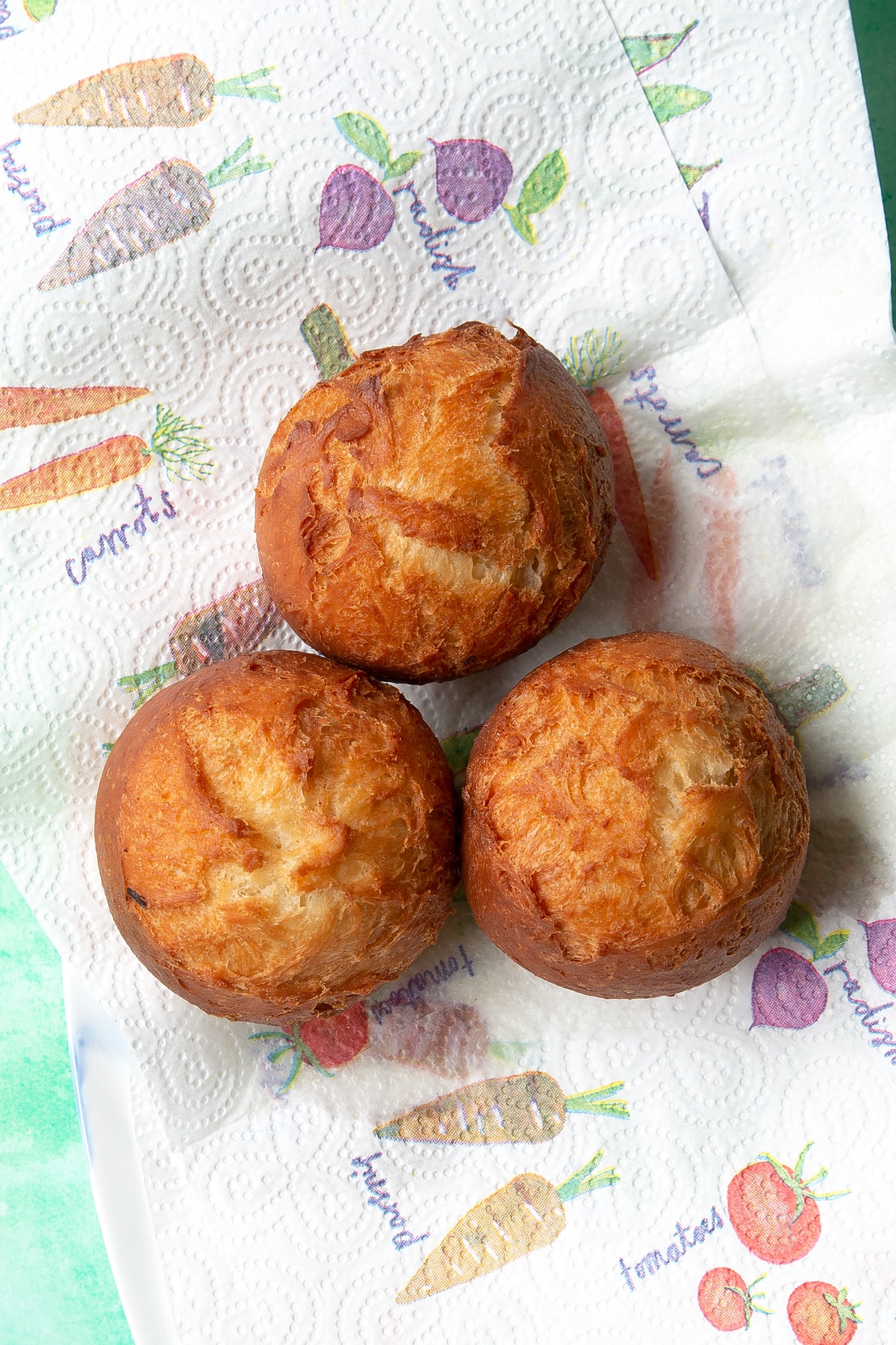 Freshly fried chicken doughnuts draining on kitchen paper.