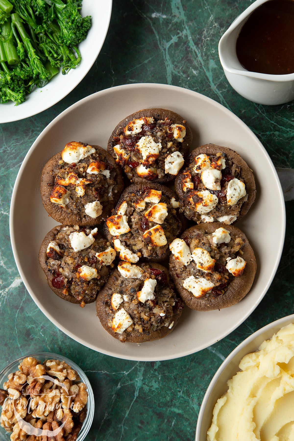 Overhead shot of crispy stuffed mushrooms topped with goats cheese served on a gray plate