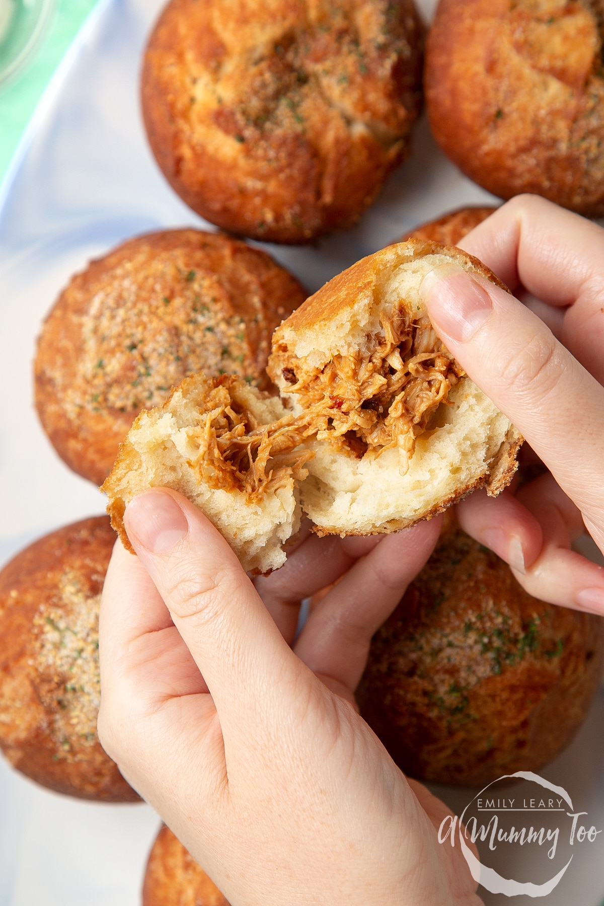 Hands tear apart a pulled chicken doughnut.