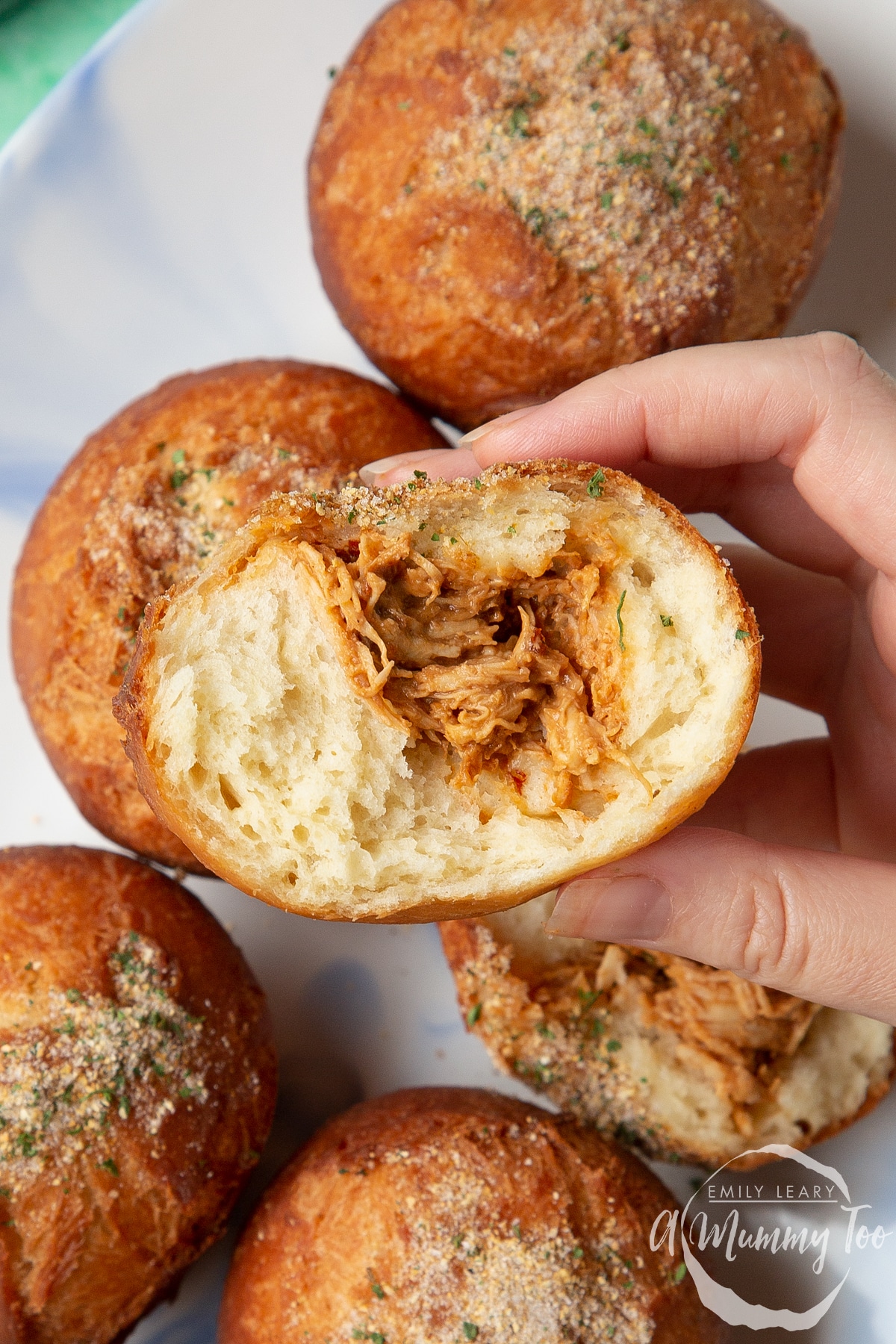 Hand holding a torn open pulled chicken doughnut.