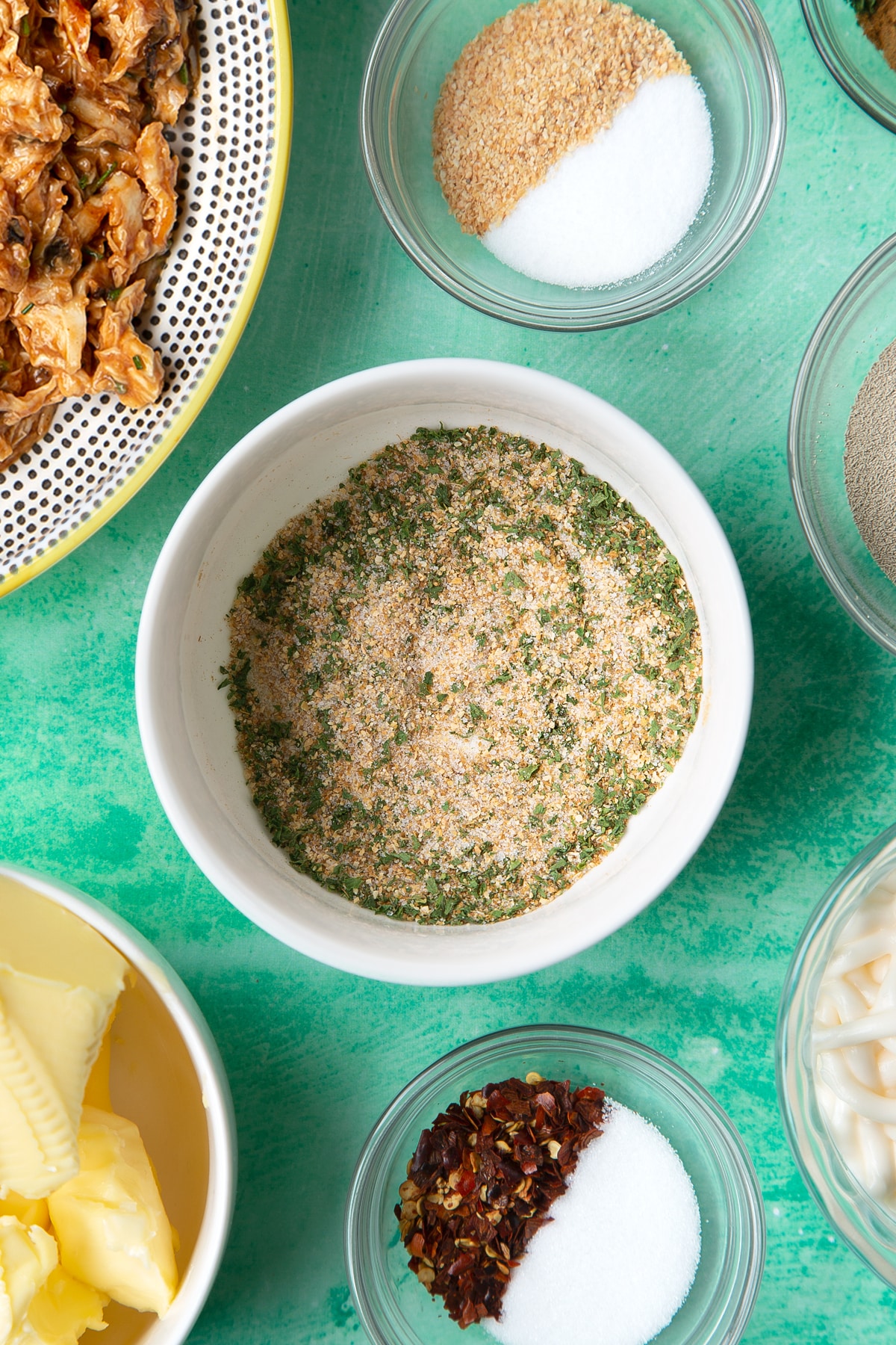 A small white bowl containing cumin, garlic granules, sugar, salt and dried coriander mixed together.