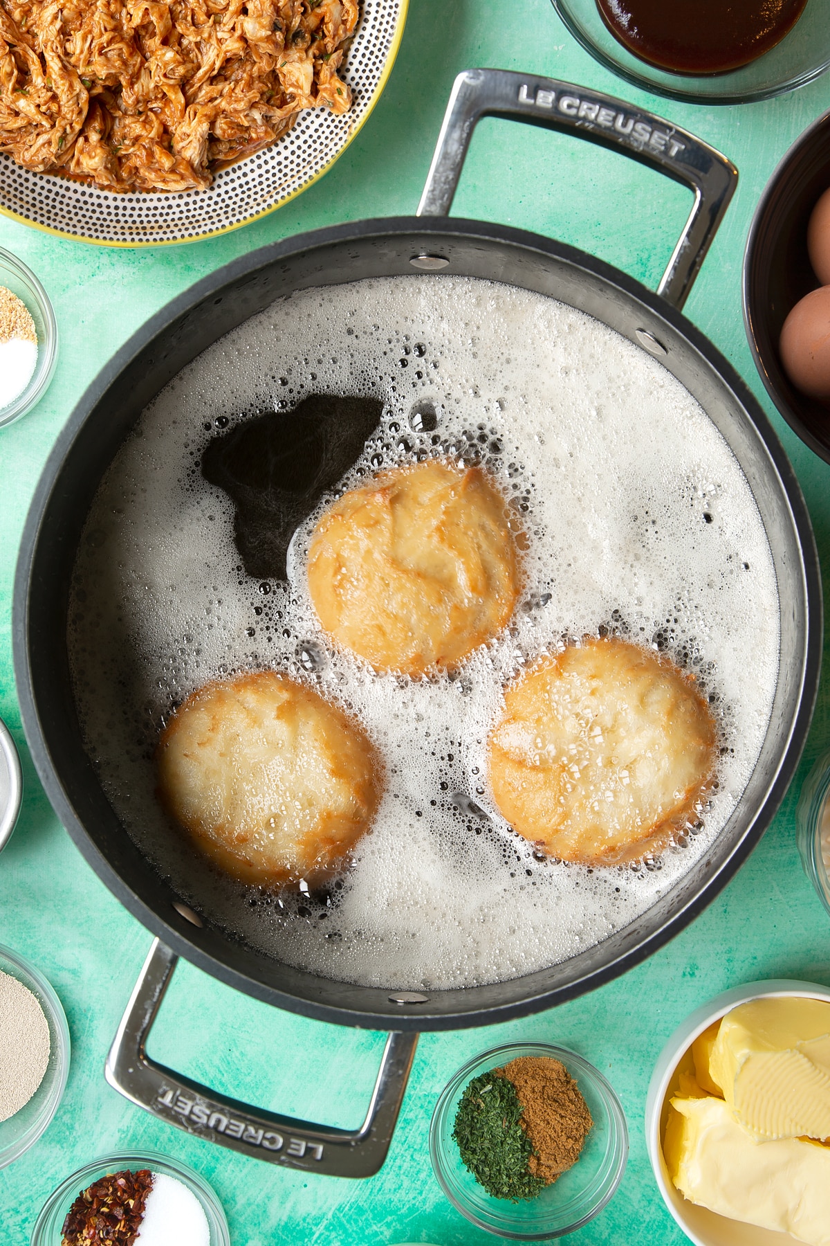 Chicken doughnuts deep frying in a large pan of oil.