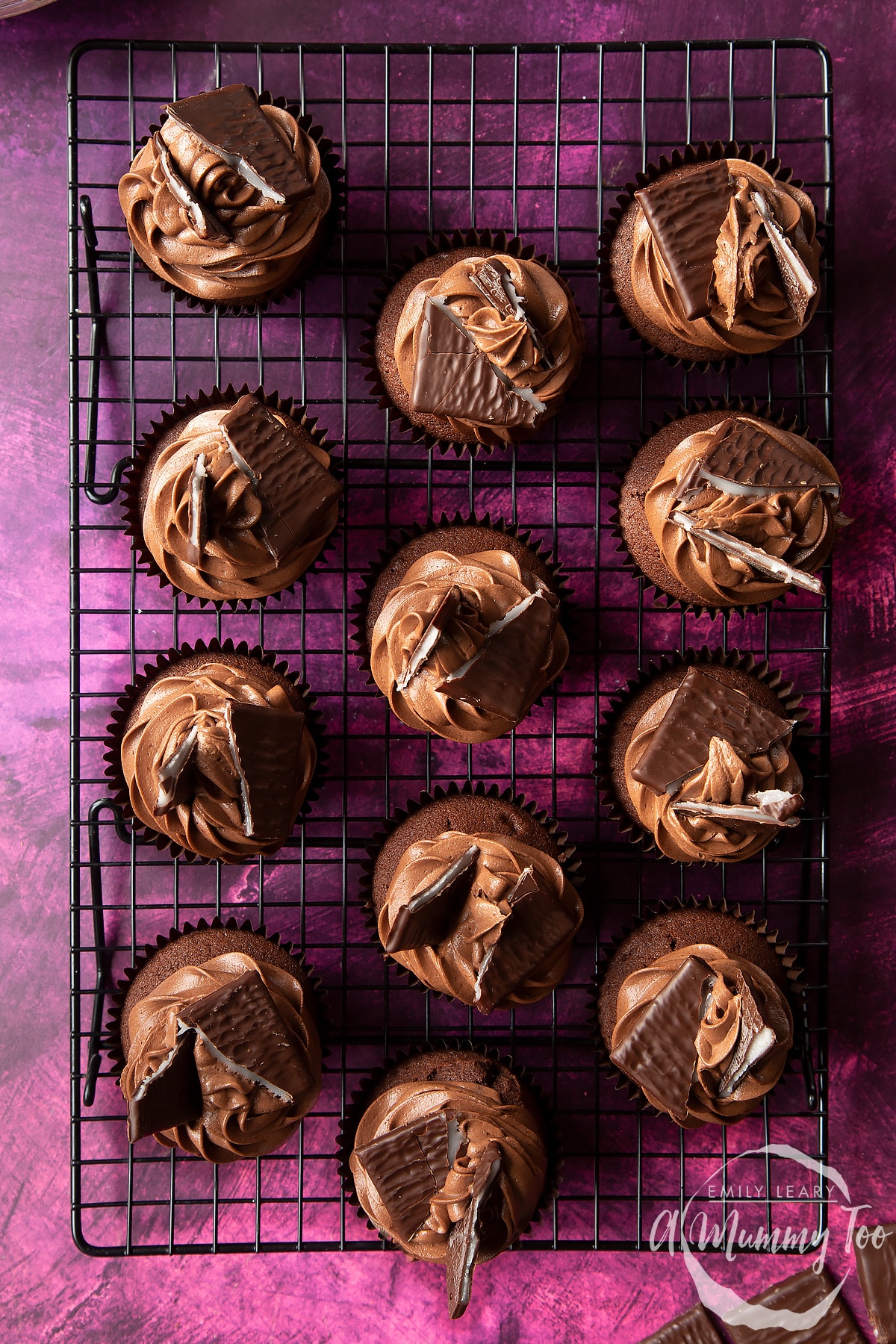 After Eight cupcakes on a cooling rack on a purple surface.
