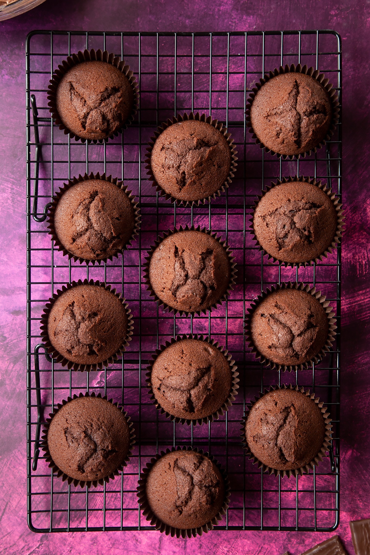 12 chocolate cupcakes on a wire cooling rack.