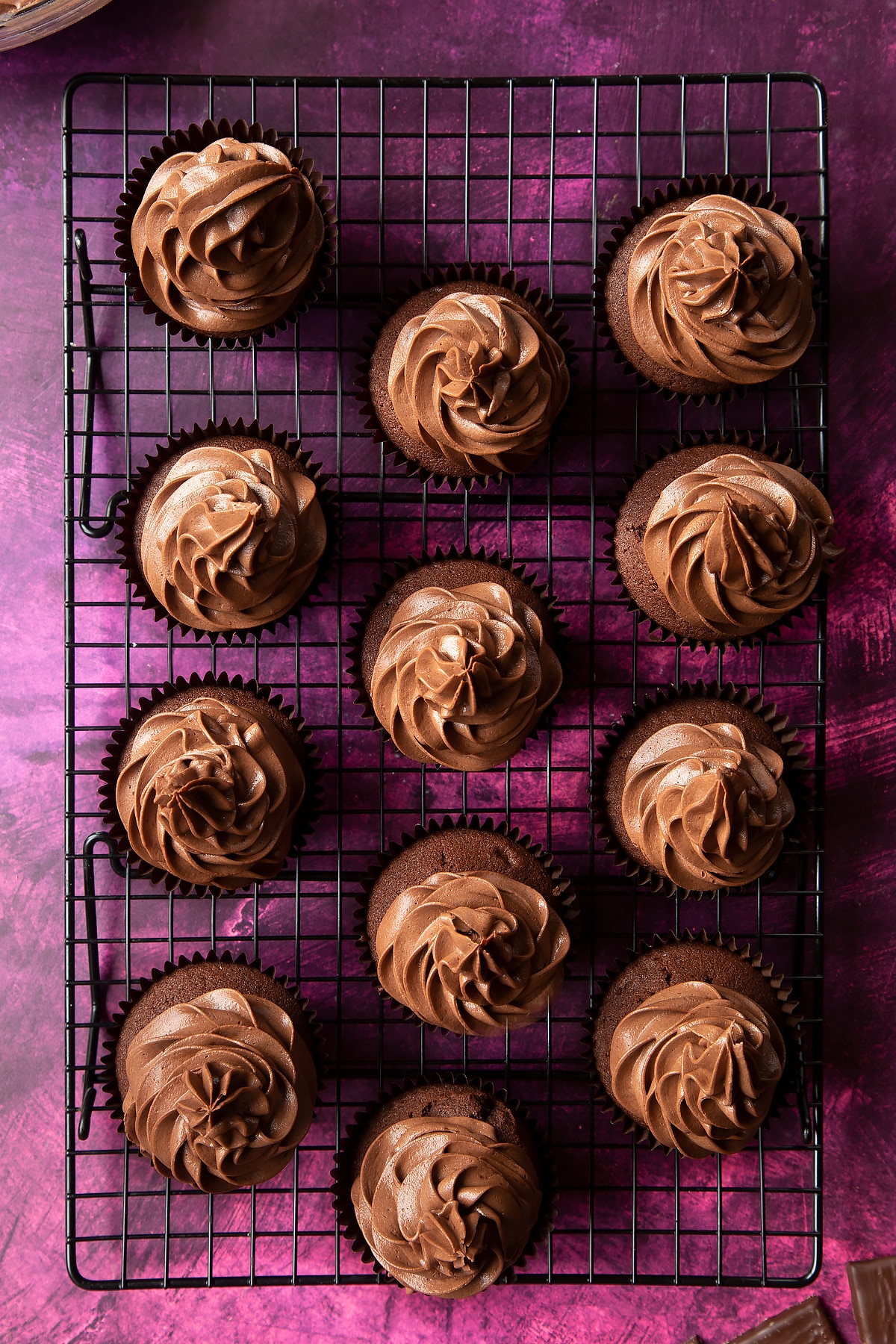 12 chocolate cupcakes on a wire rack. After Eight buttercream has been piped in swirls on top.