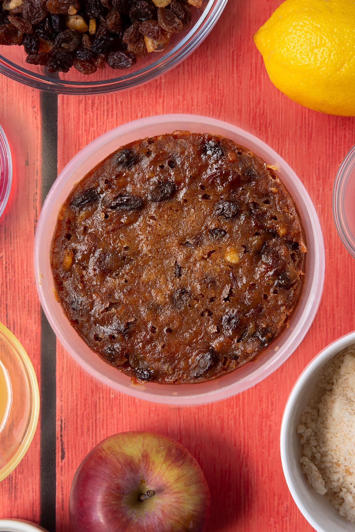 Overhead shot of the finished Christmas pudding in a bowl on a red table.