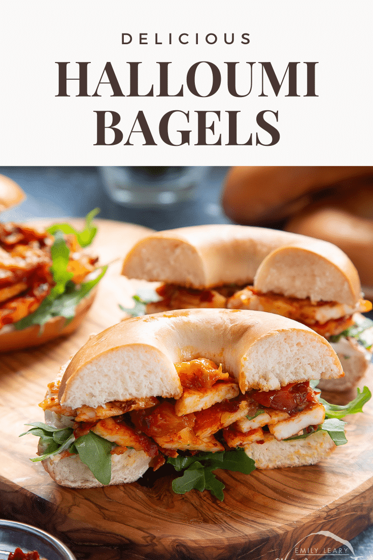 Two halloumi bagels on a wooden board. One is cut in half. Caption reads: delicious halloumi bagels