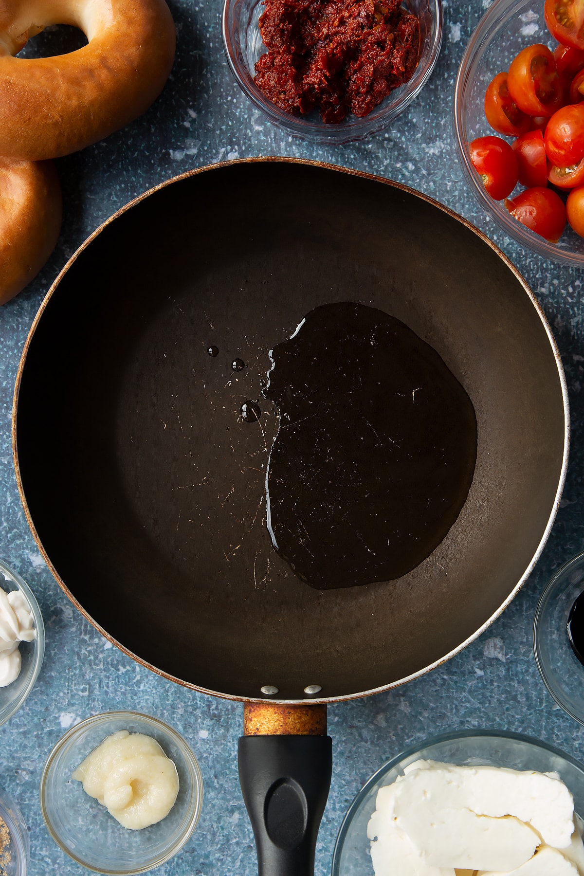 Oil in a frying pan. Ingredients to make halloumi bagels surround the pan.