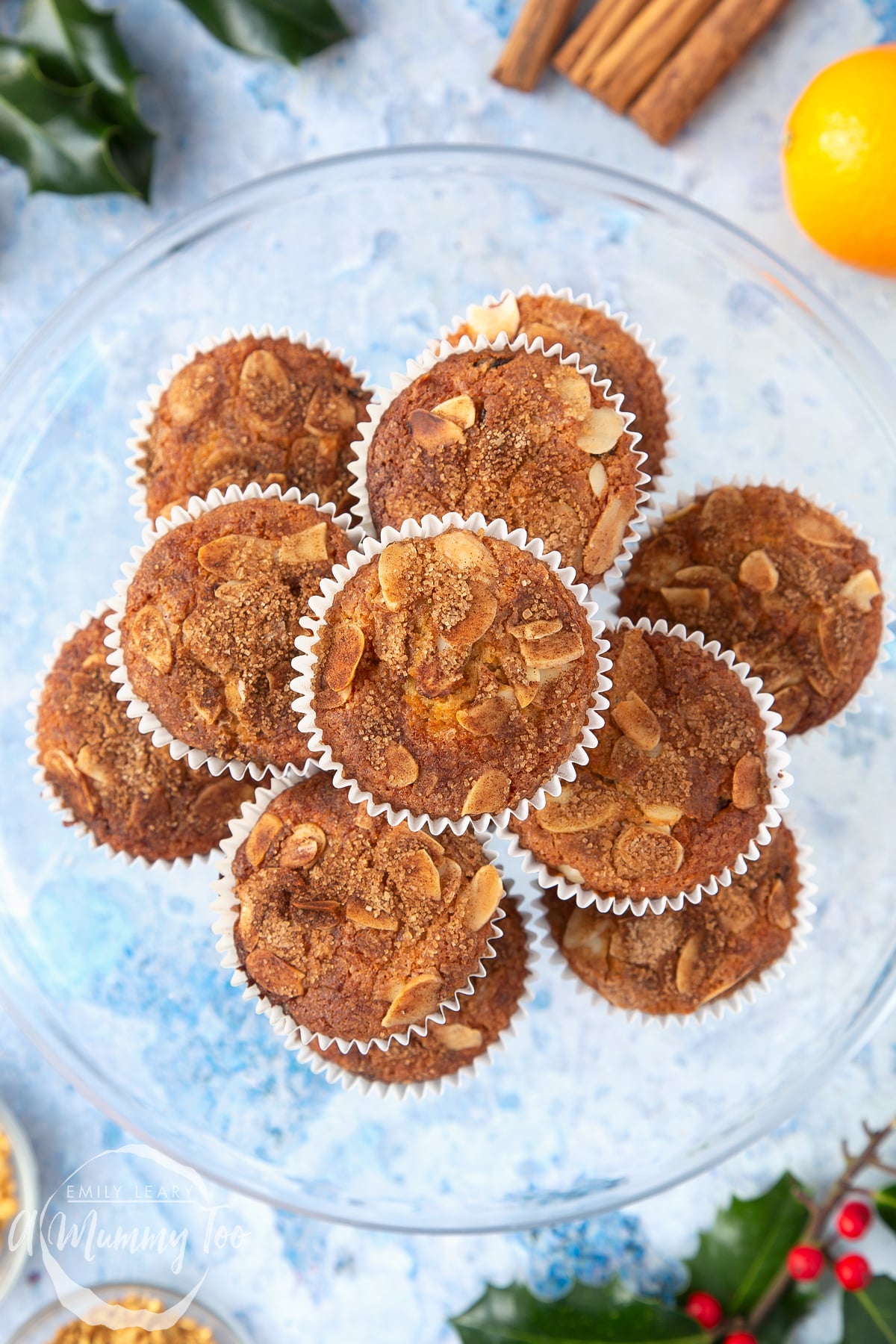Overhead shot of baked orange and cinnamon muffins stacked in a large clear bowl