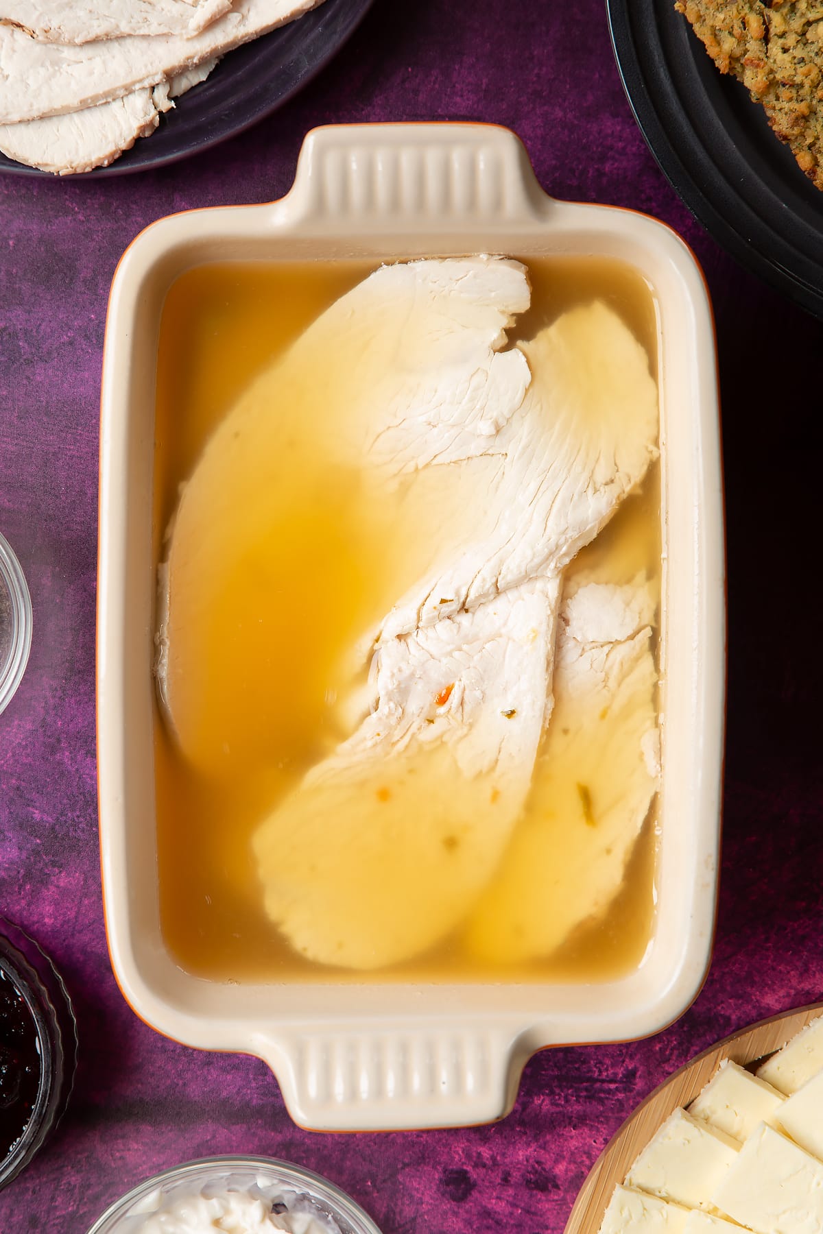 Overhead shot of turkey slices covered with hot chicken stock in a small rectangular dish