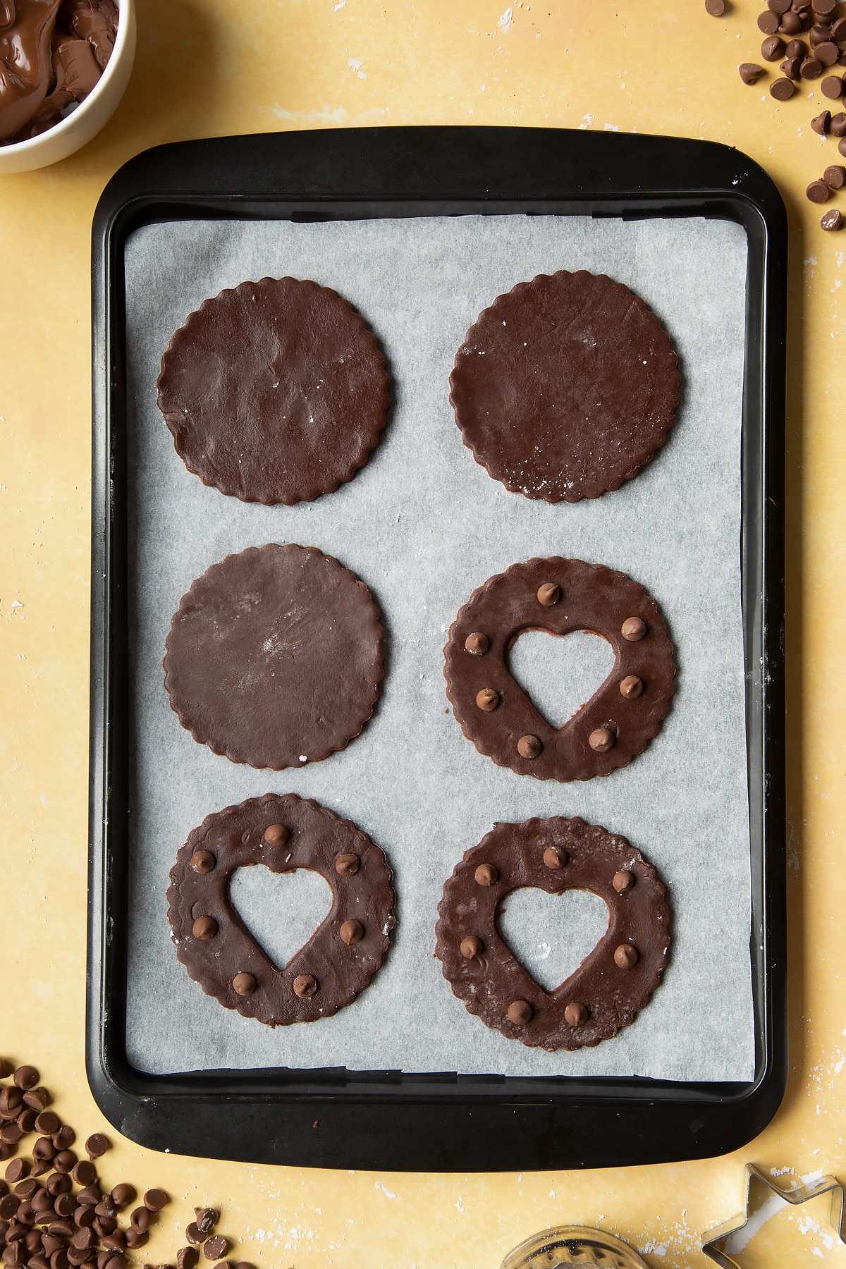 Raw chocolate sandwich cookies on a tray lined with baking paper.
