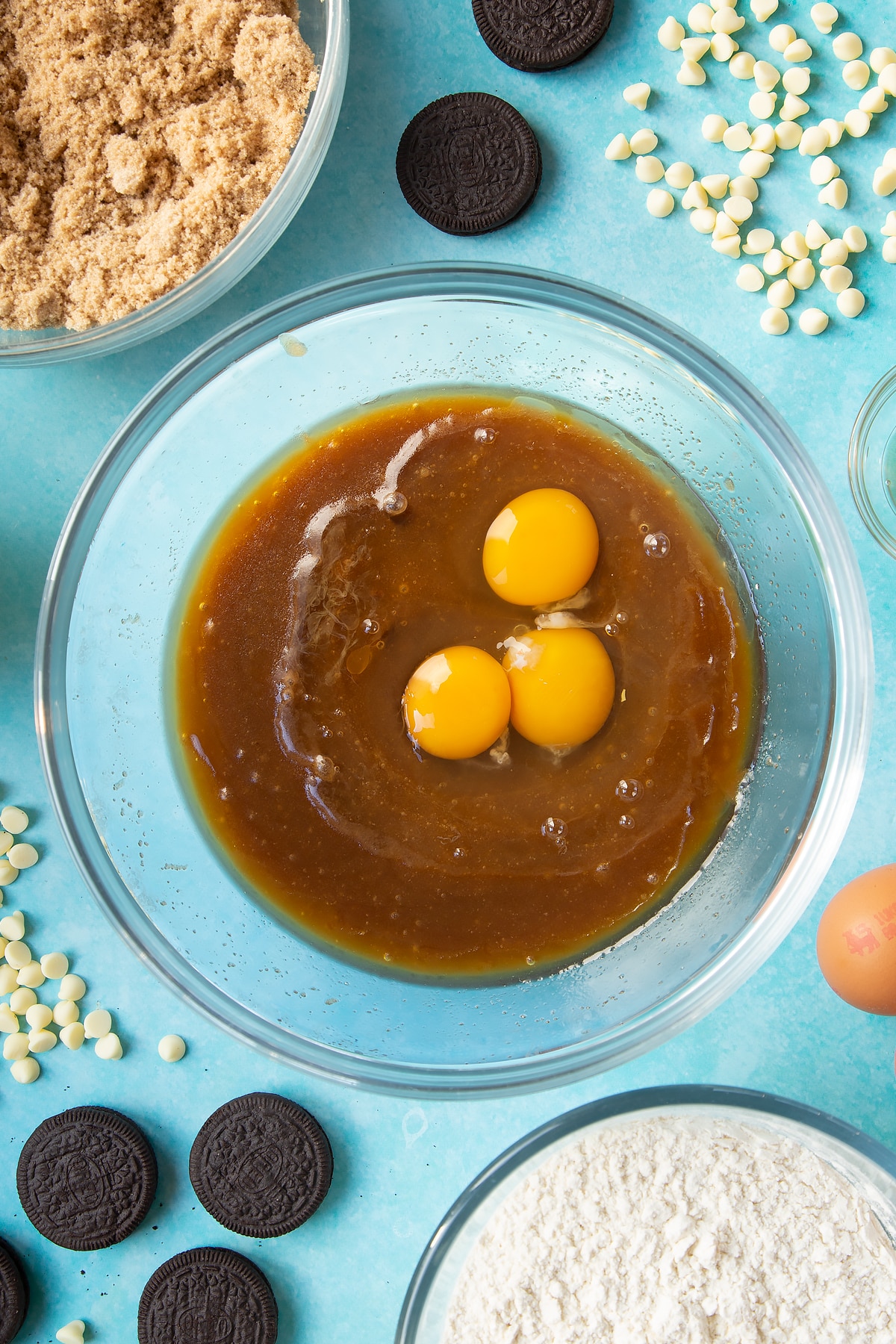 Overhead shot of brown sugar butter mix with vanilla and 3 eggs in a large clear bowl