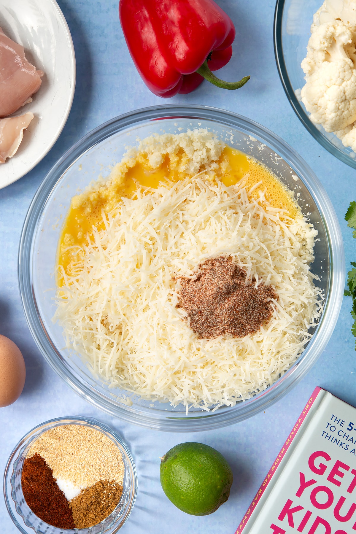 Very finely chopped cauliflower, eggs, grated cheese and taco seasoning in a bowl.