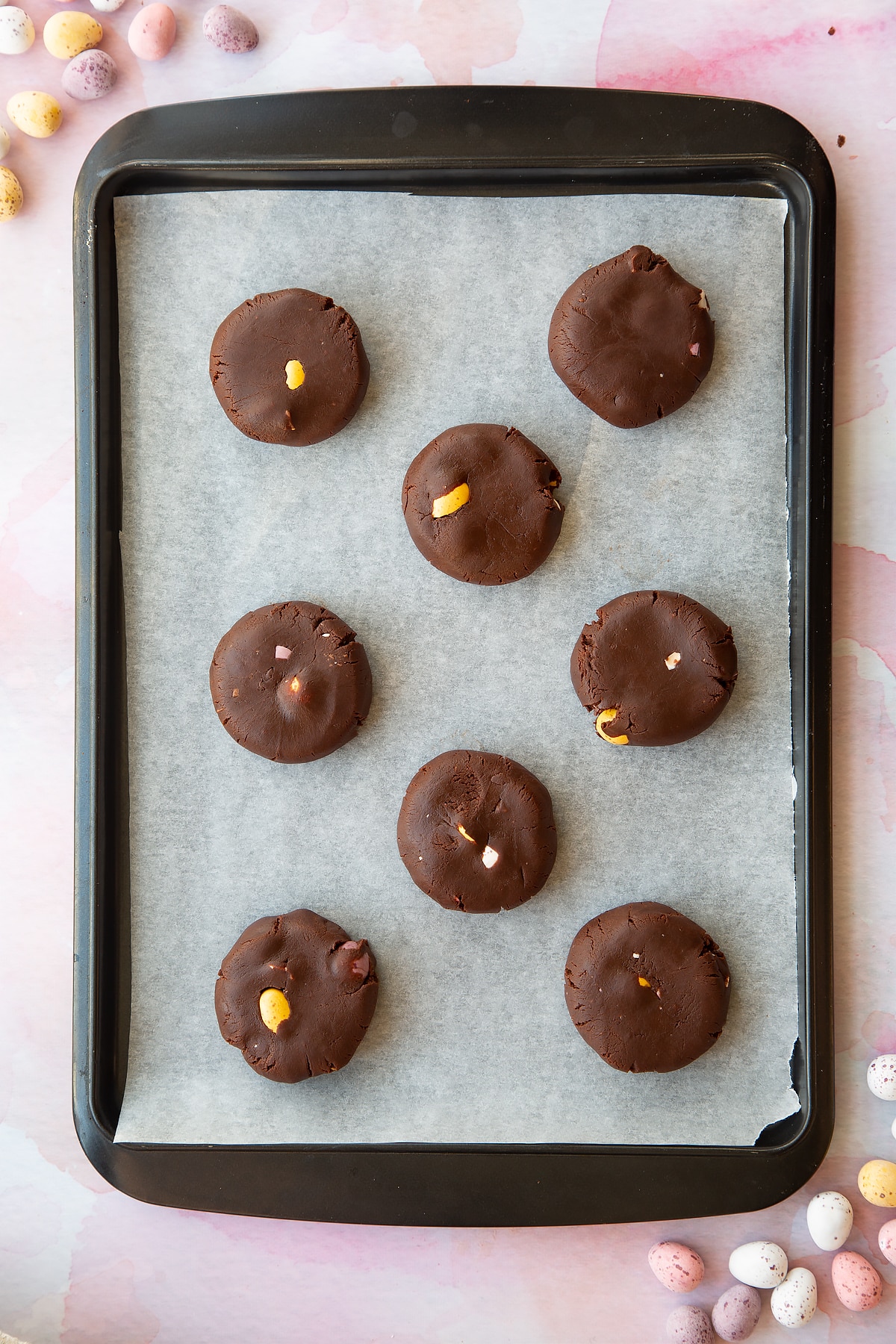 Chocolate Easter cookie dough discs on a tray lined with baking paper.