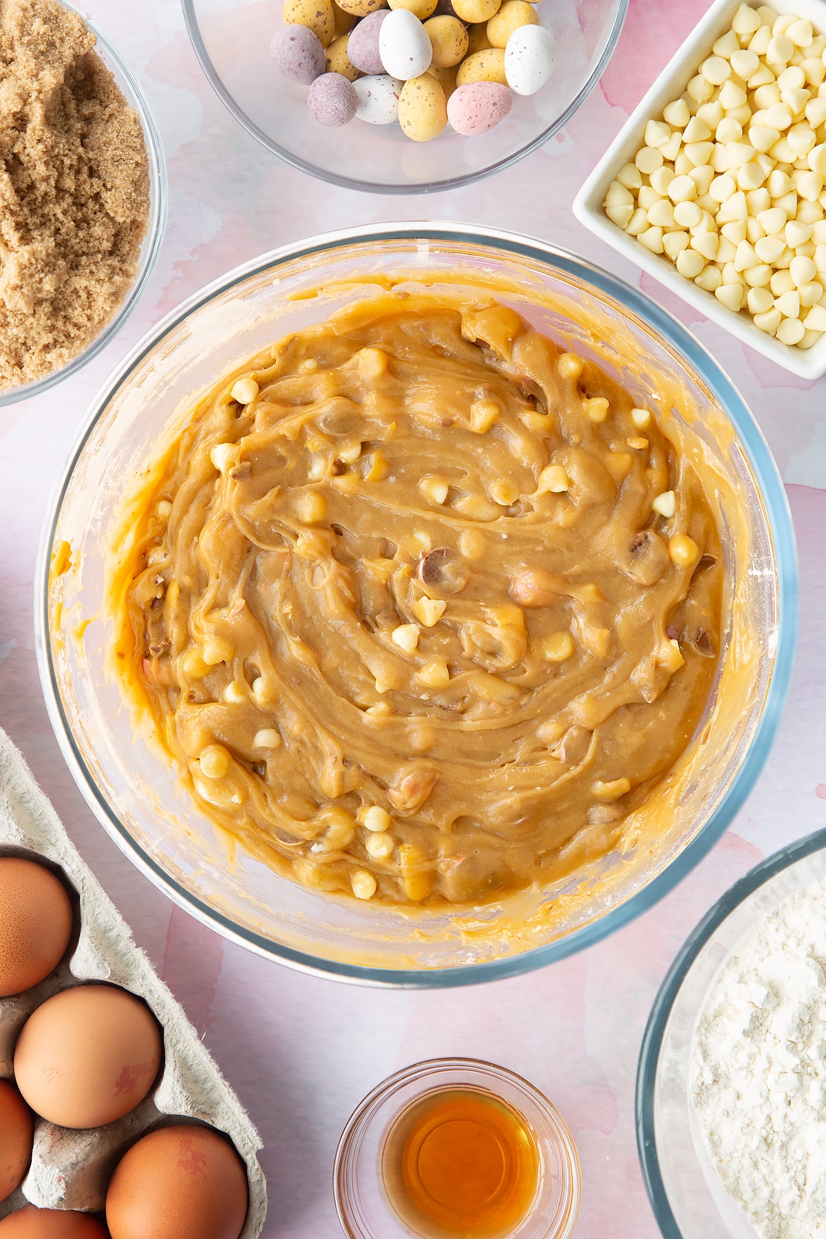 Mini Egg blondie batter in a bowl. Ingredients to make Mini Egg blondies surround the bowl.