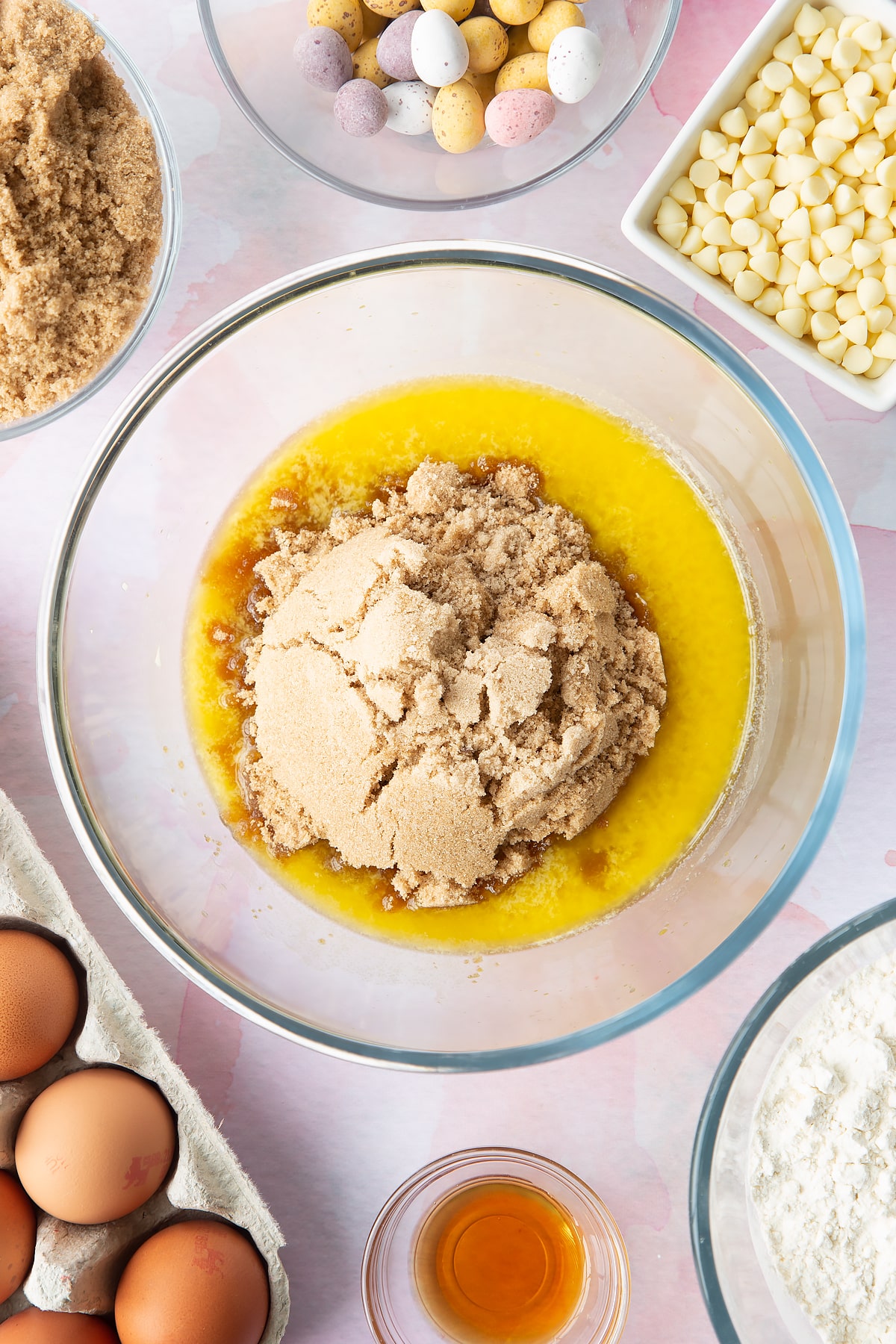 Melted butter and sugar in a bowl. Ingredients to make Mini Egg blondies surround the bowl.