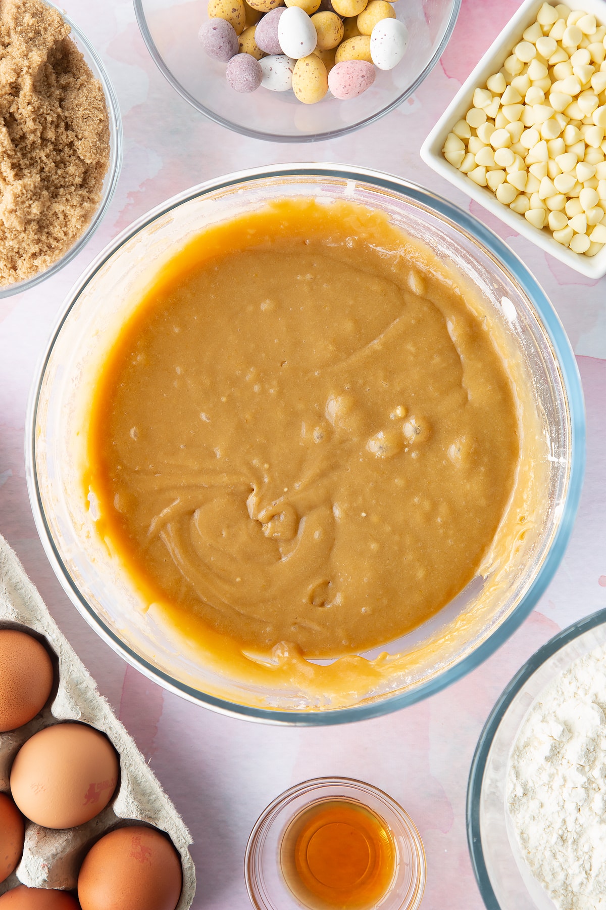 Basic blondie batter in a bowl. Ingredients to make Mini Egg blondies surround the bowl.