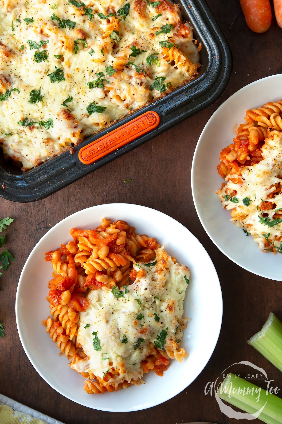 Pasta and baked beans served to white bowls with melted mozzarella.