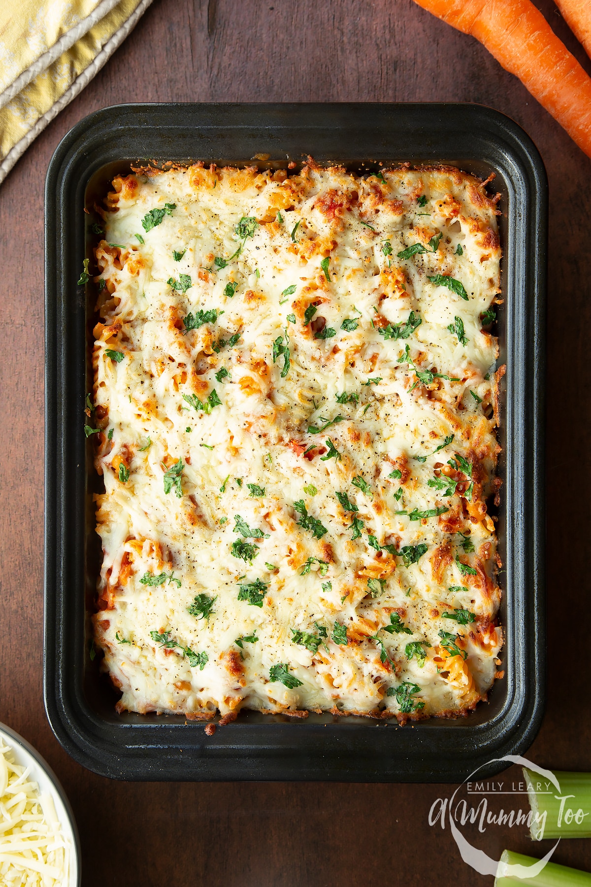 Freshly cooked pasta and baked beans in a tray. Ingredients to make pasta and baked beans surround the tray.