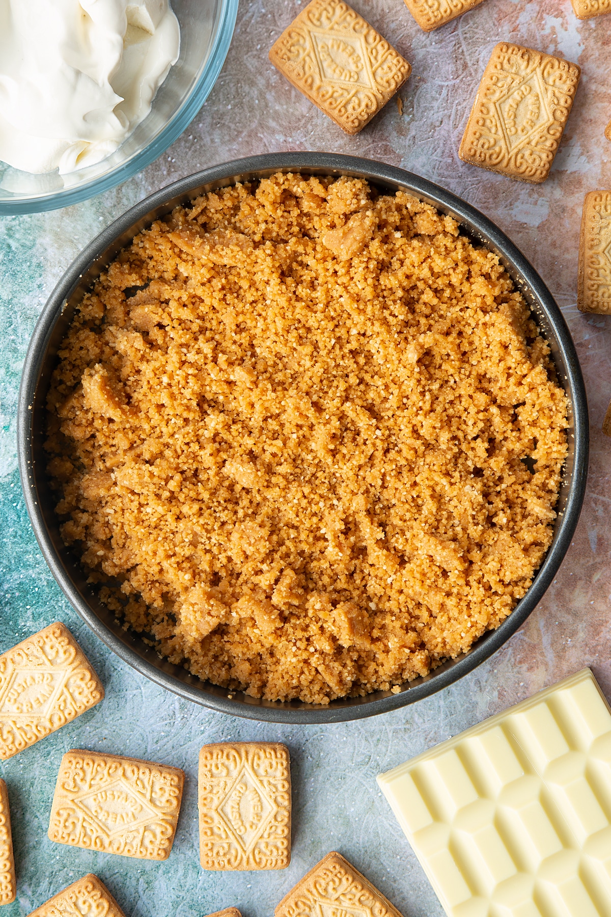 Overhead shot of custard cream biscuit crumbs in a large metal cake tin