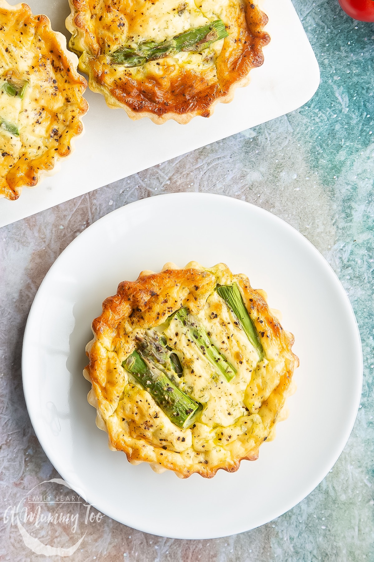 Close up of an asparagus tartlet on a white plate, shown from above.