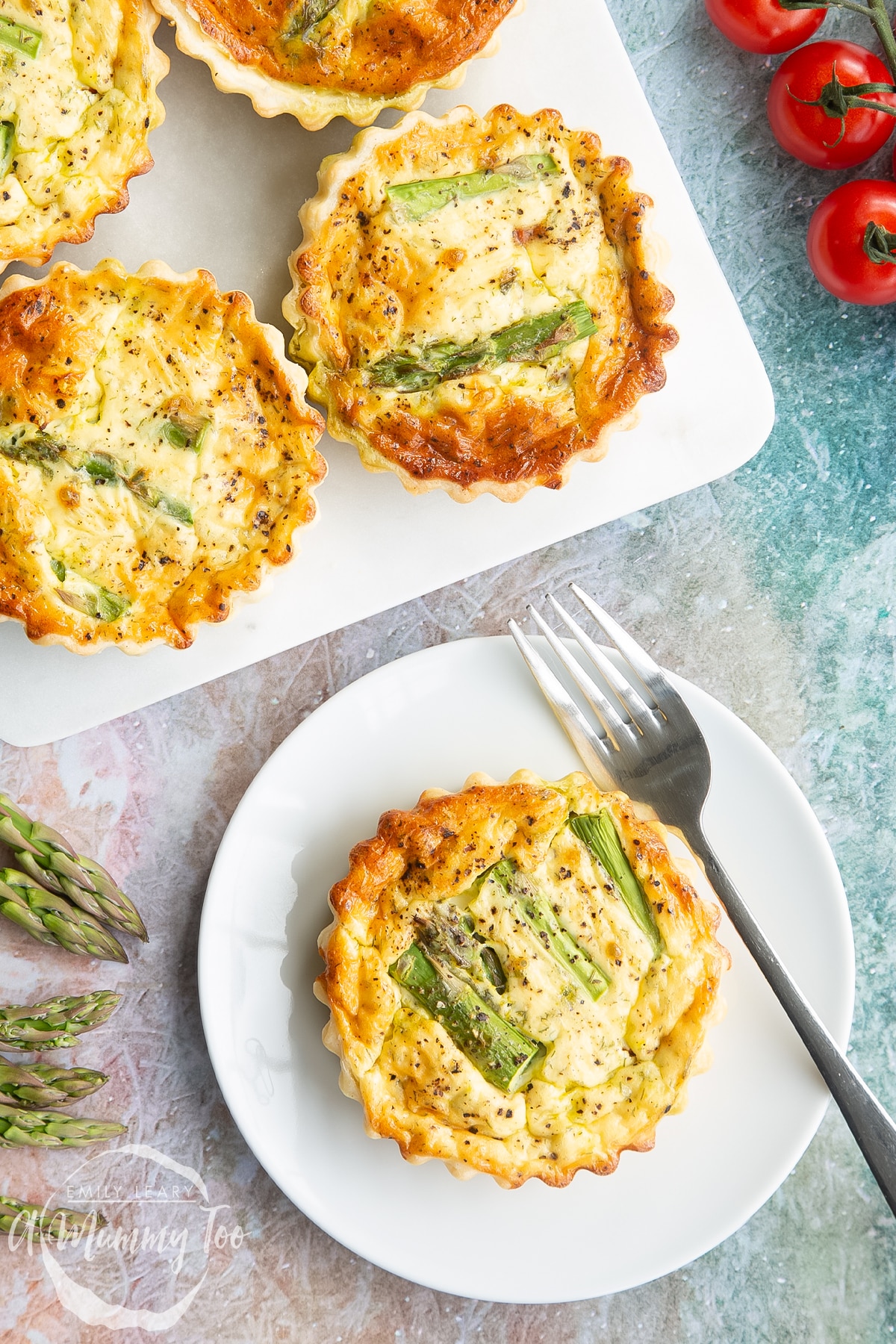Asparagus tartlets on a white plate with a fork in close up.