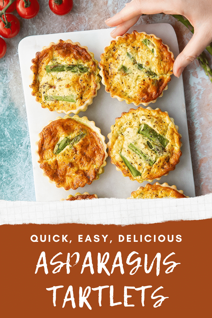 Asparagus tartlets on a white marble board. A hand reaches for one. Caption reads: quick, easy, delicious asparagus tartlets