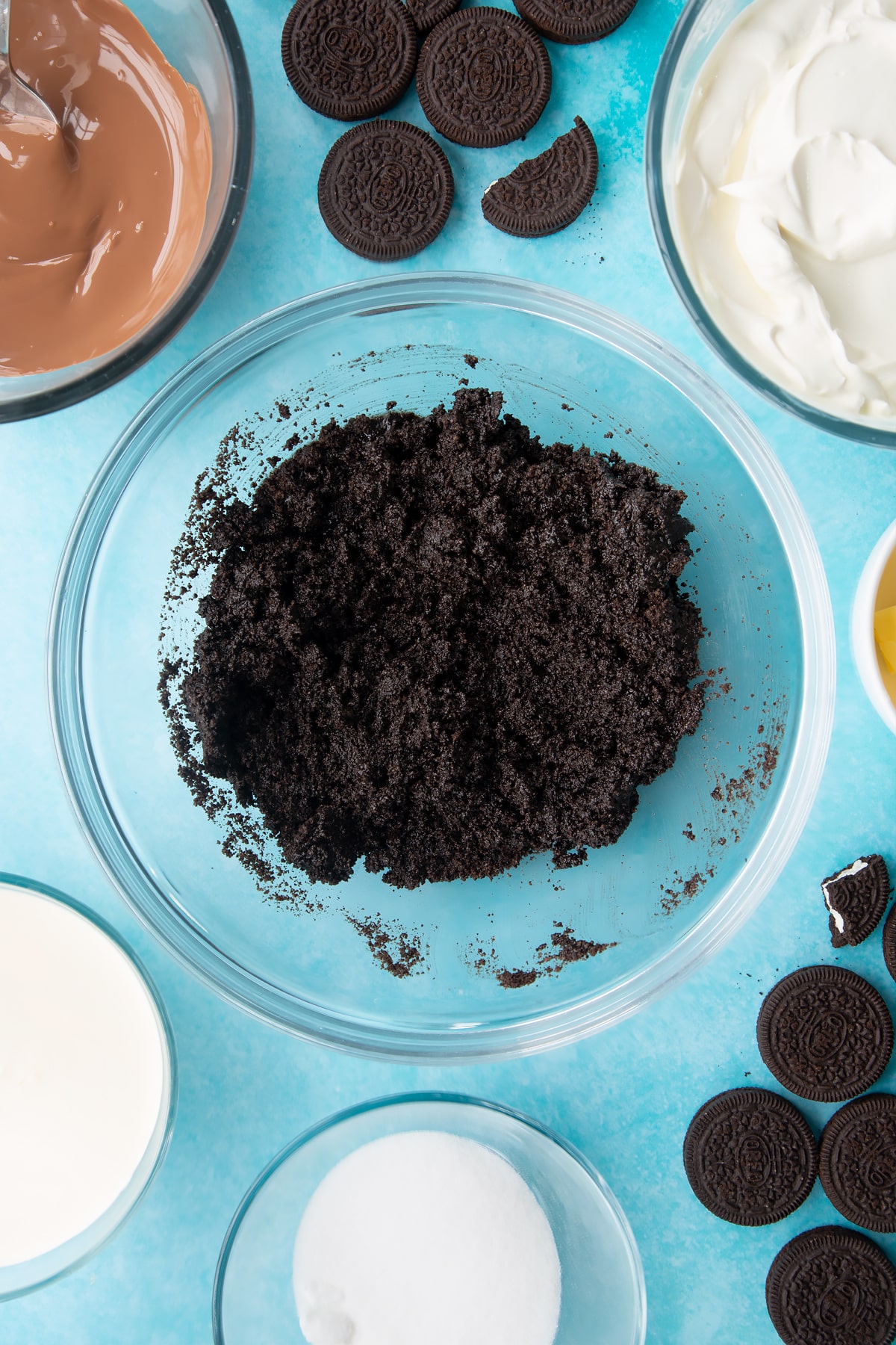Overhead shot of oreo biscuits crumb with melted butter mixed together in a large clear bowl