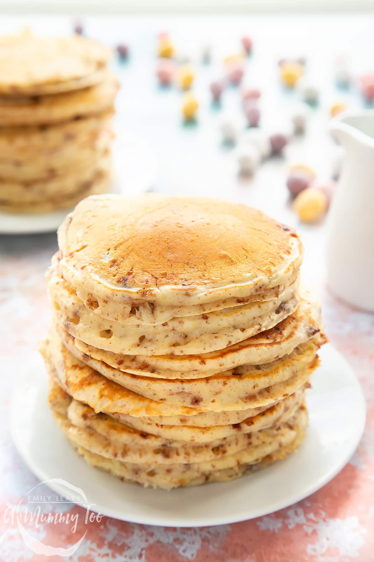 Thick, fluffy Mini Egg pancakes on a white plate in a tall stack.