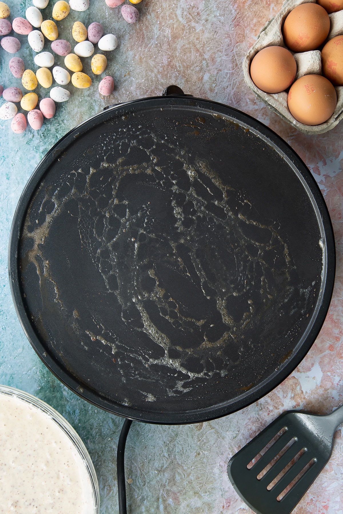 Melted butter on a hot pan. Ingredients to make Mini Egg pancakes surround the pan.