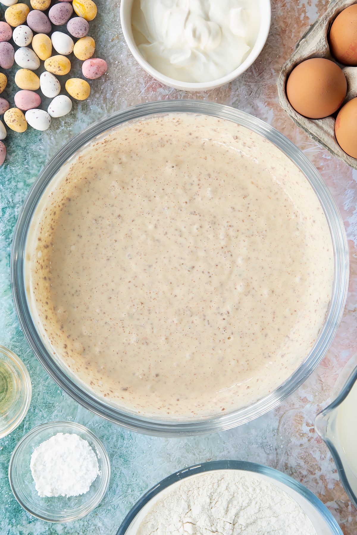 Mini Egg pancake batter in a bowl. Ingredients to make Mini Egg pancakes surround the bowl.