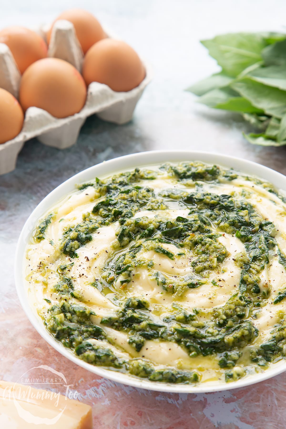 Pesto mayo in a white bowl. The pesto and mayonnaise are swirled together.