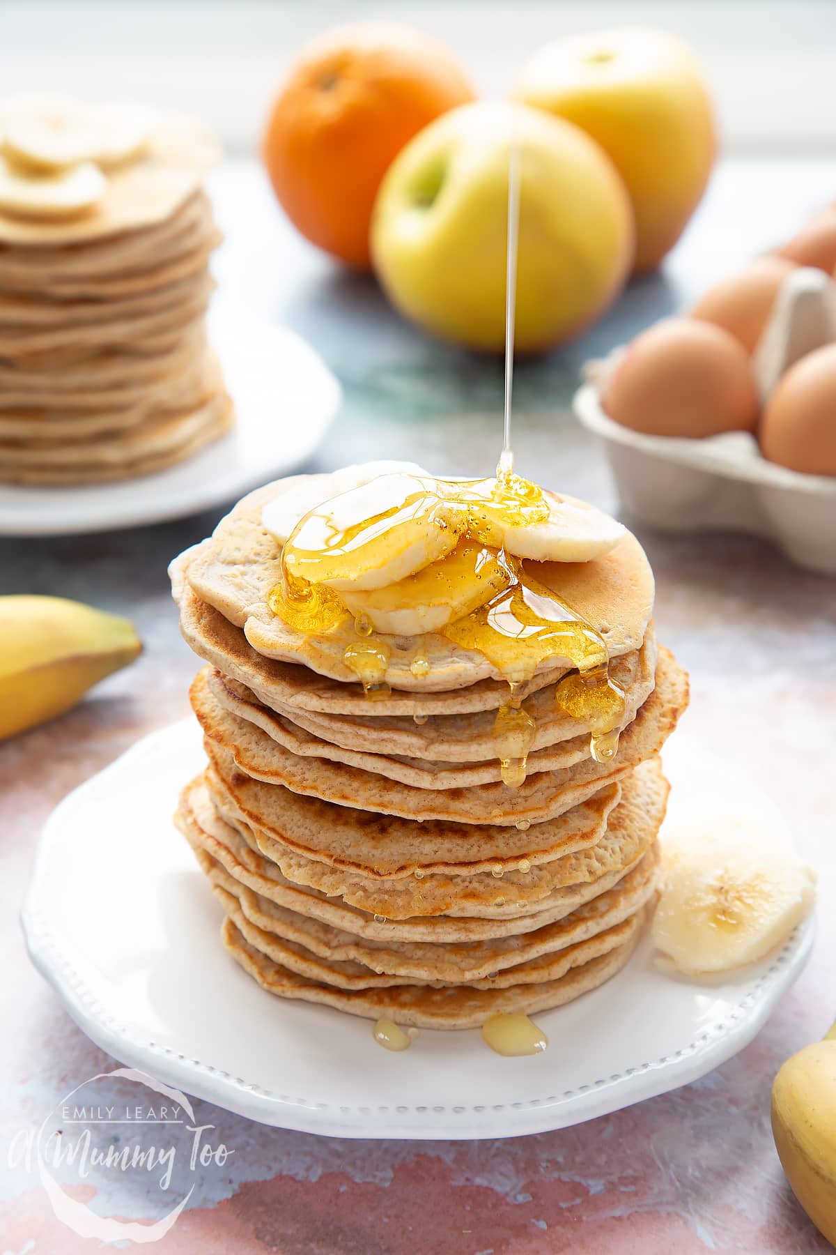 A stack of fluffy pancakes topped with syrup and banana on a white plate