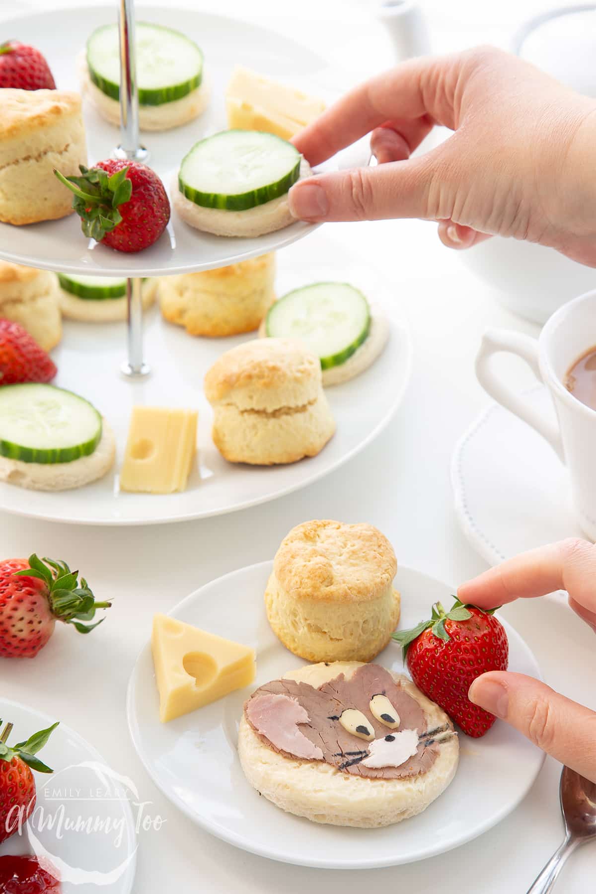 Hand picking up different pieces of food from the Tom and Jerry afternoon tea platter.