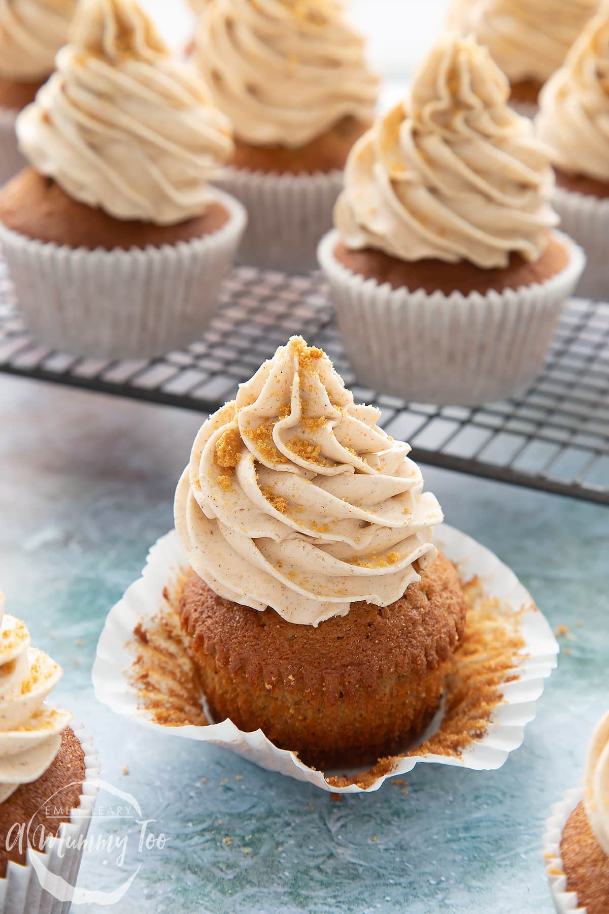 Ginger cupcake on a blue background. The cupcake is partly unwrapped.
