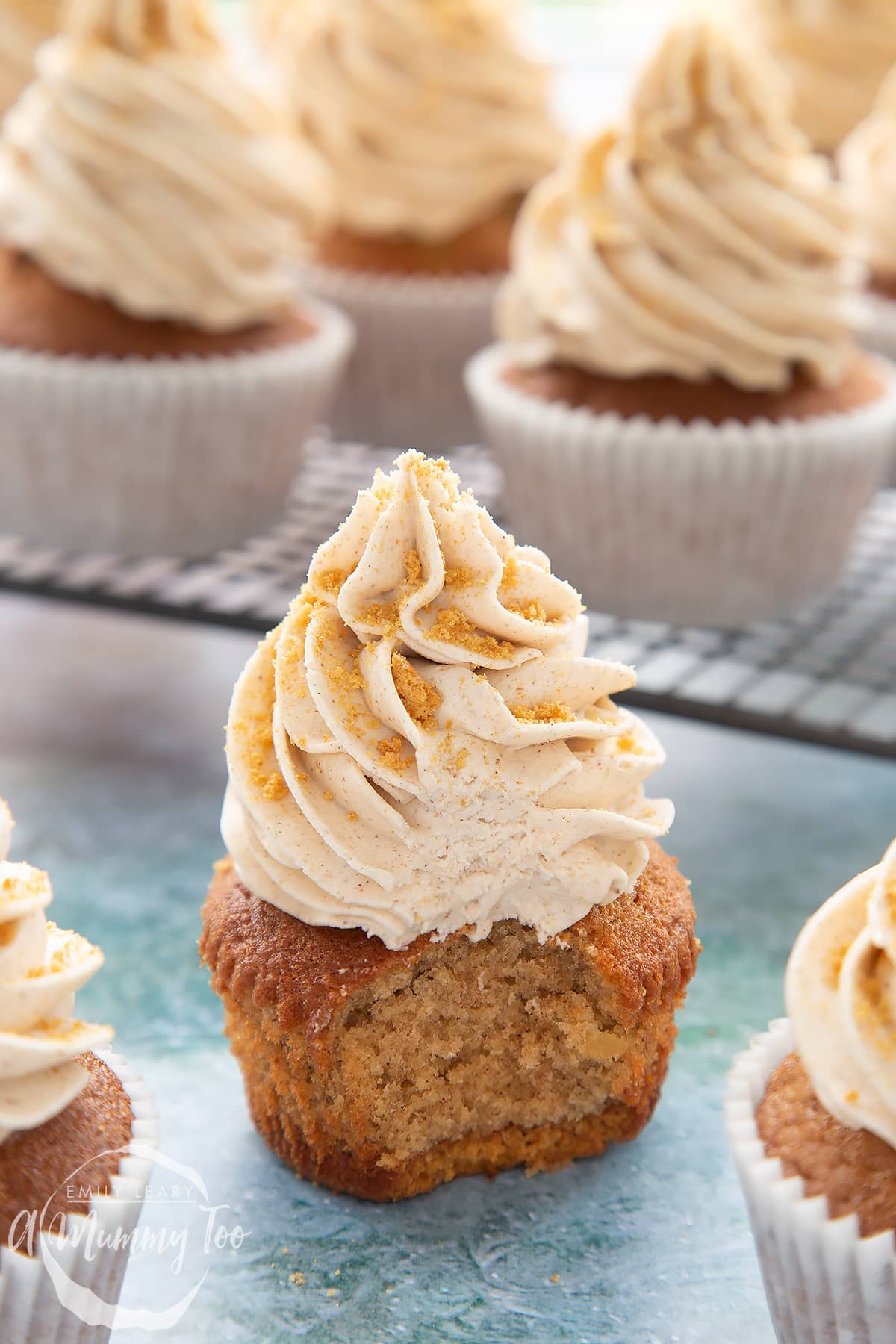 Ginger cupcake on a blue background. The cupcake is unwrapped and has a bite out of it.